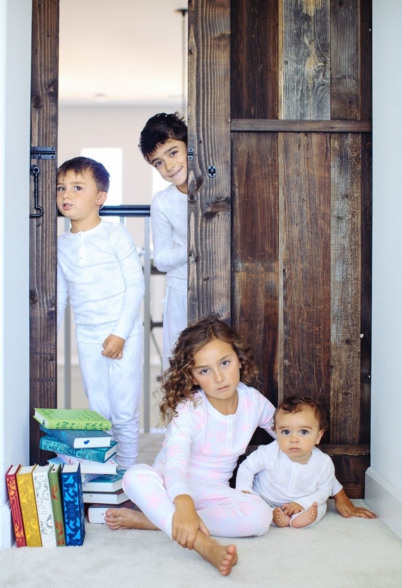 children in pajamas with pile of books