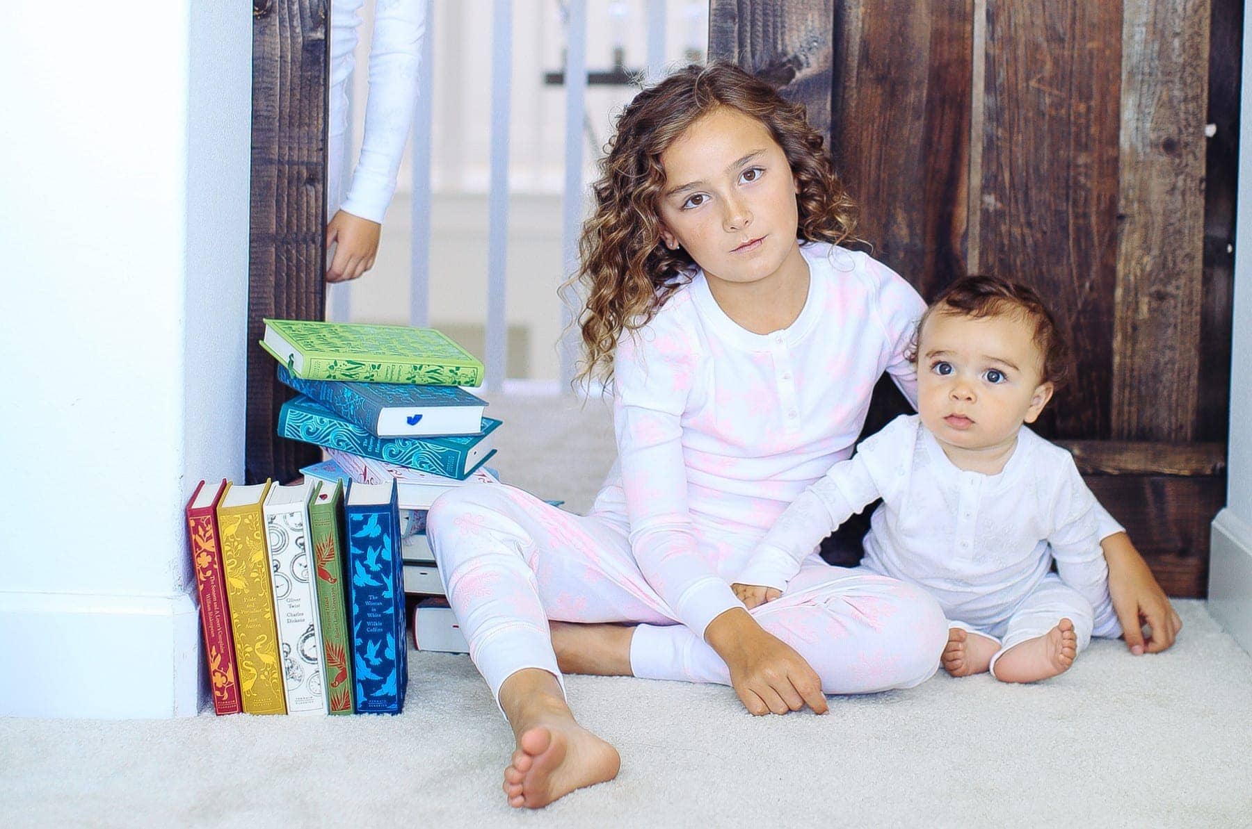 girl and baby by pile of books