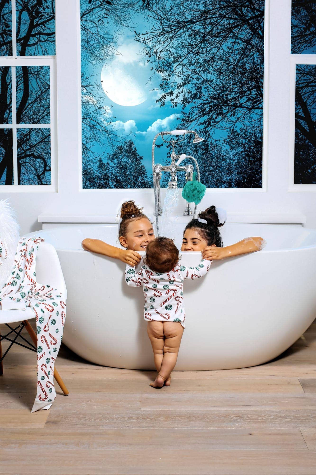 girls in bathtub with baby standing