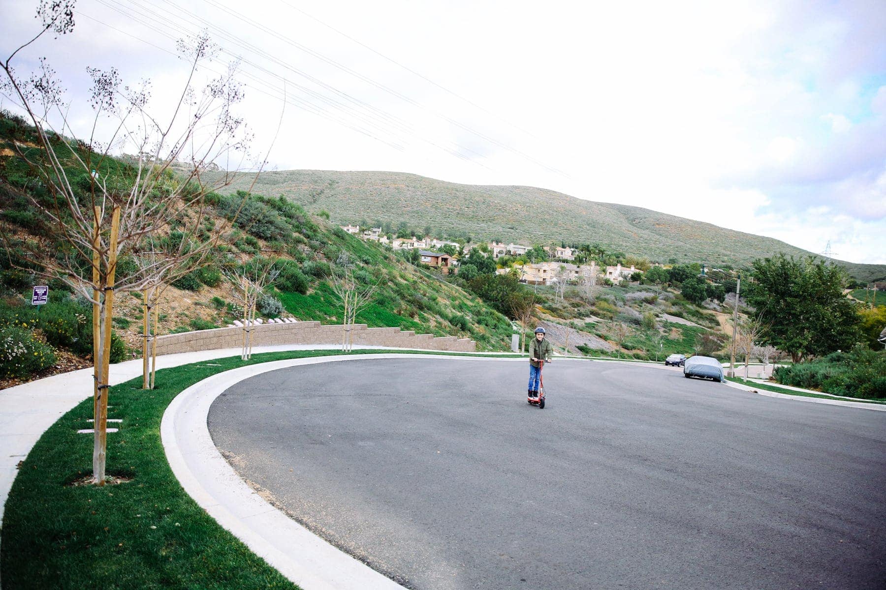 boy riding scooter down street