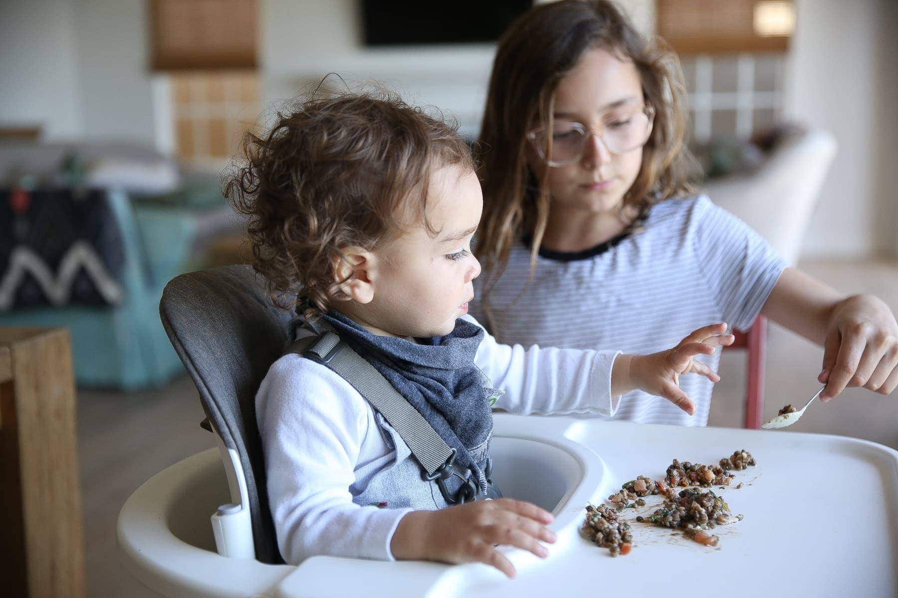 big sister feeding baby brother 