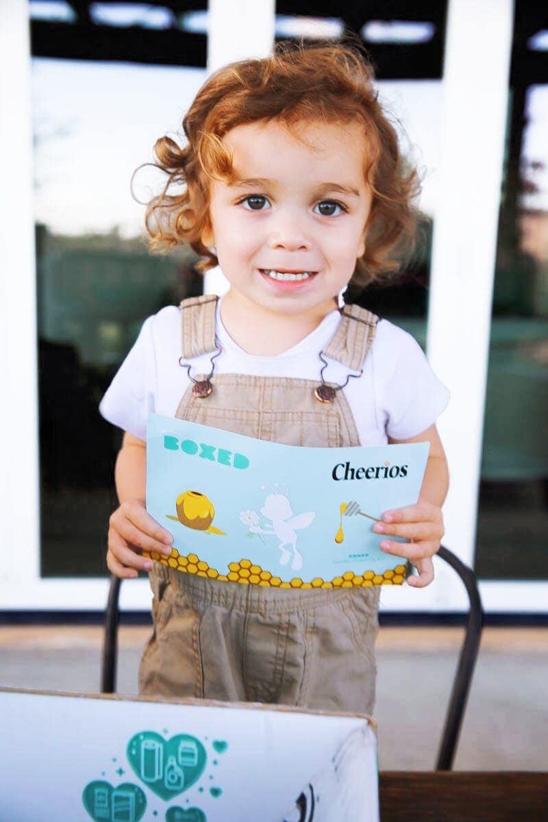 Child holding stickers from the Boxed and General Mills Bring Back the Bees campaign creativity kit