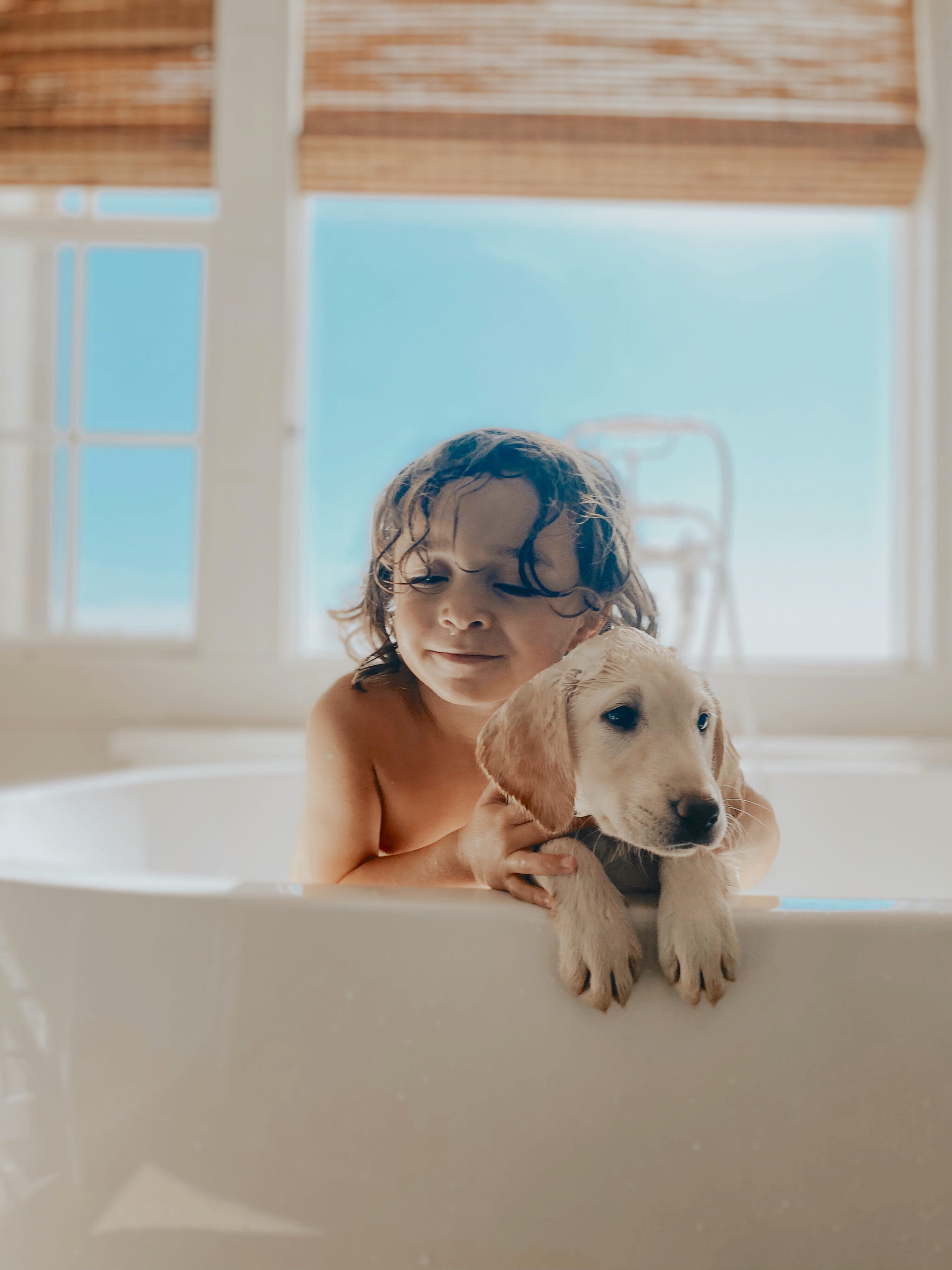 toddler and puppy in bathtub
