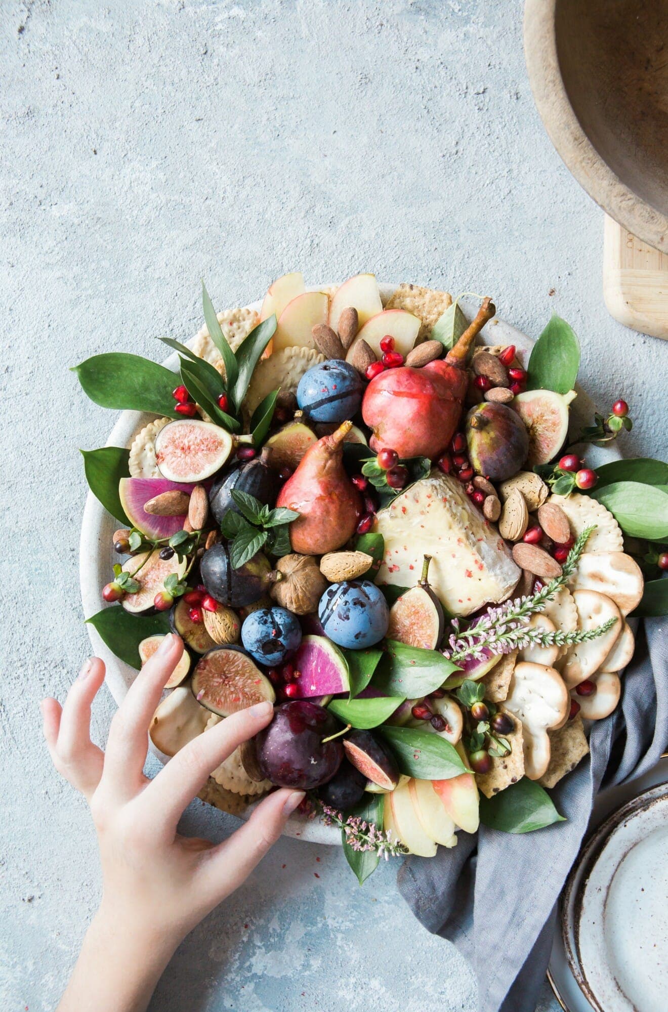 a hand reaching out to select fruit from a charcuterie board