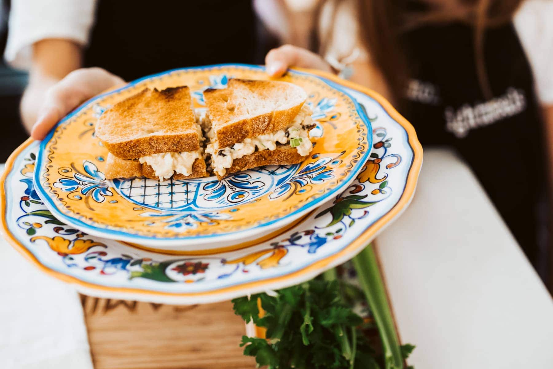 holding up a plate with a sandwich