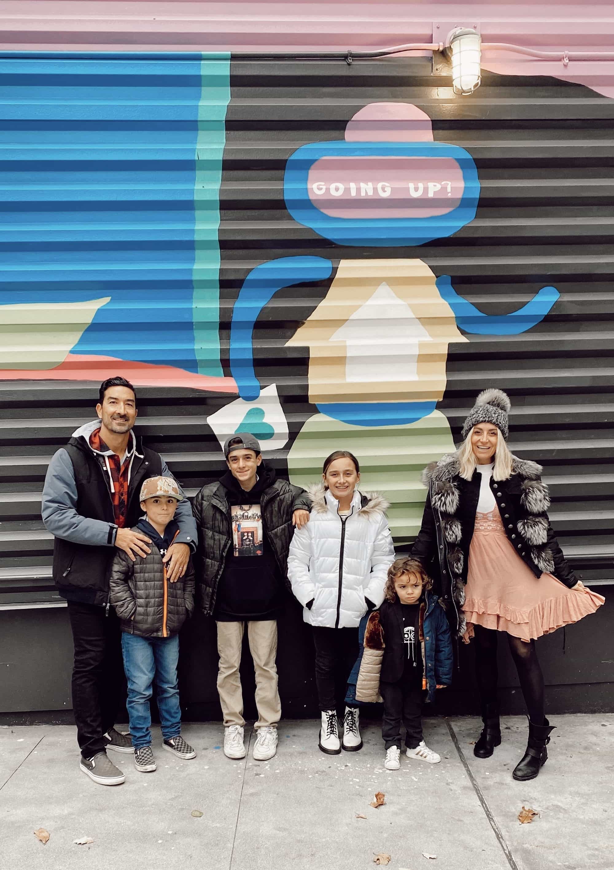 family posing by mural