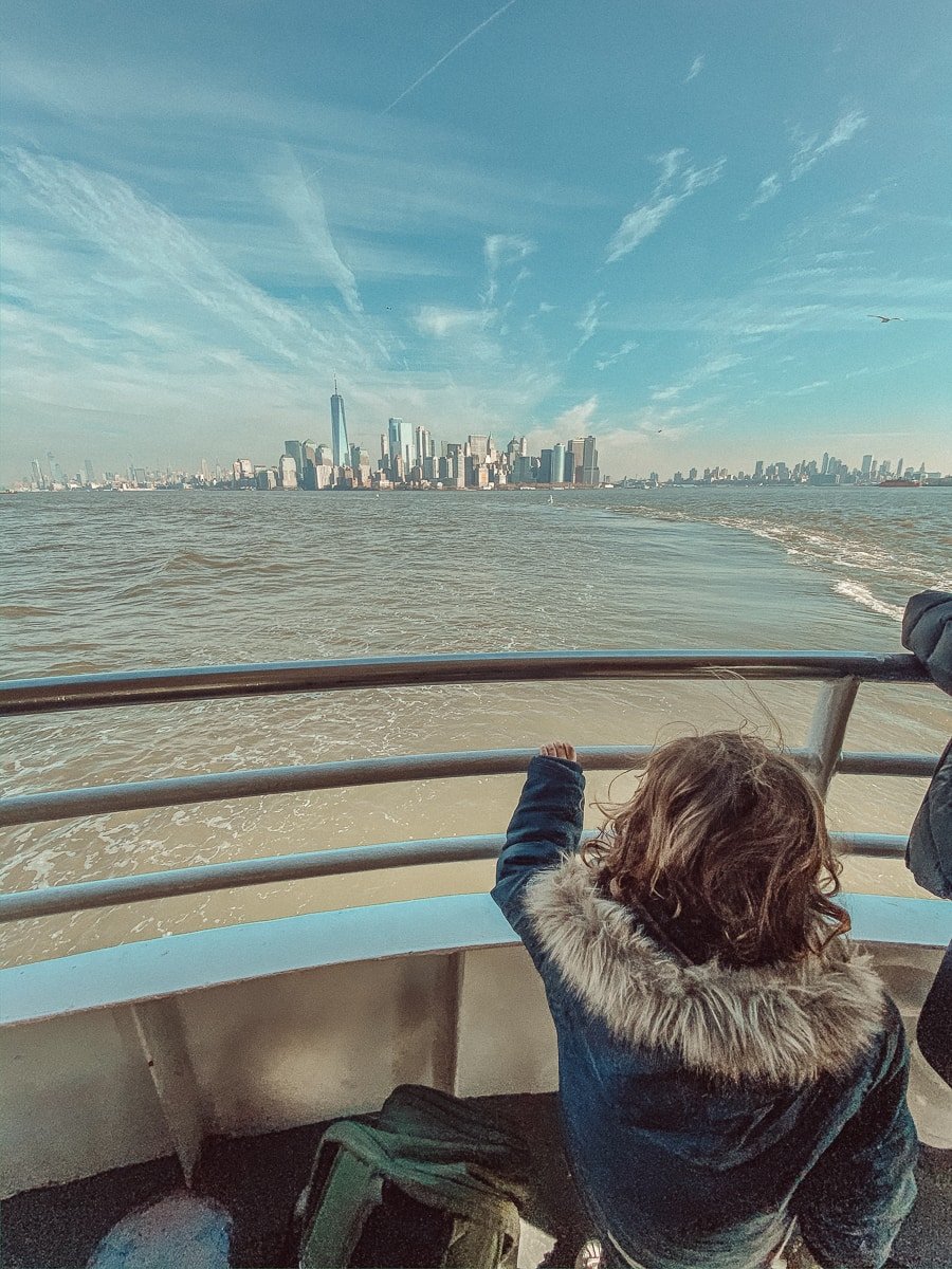 toddler on boat with new york city skyline