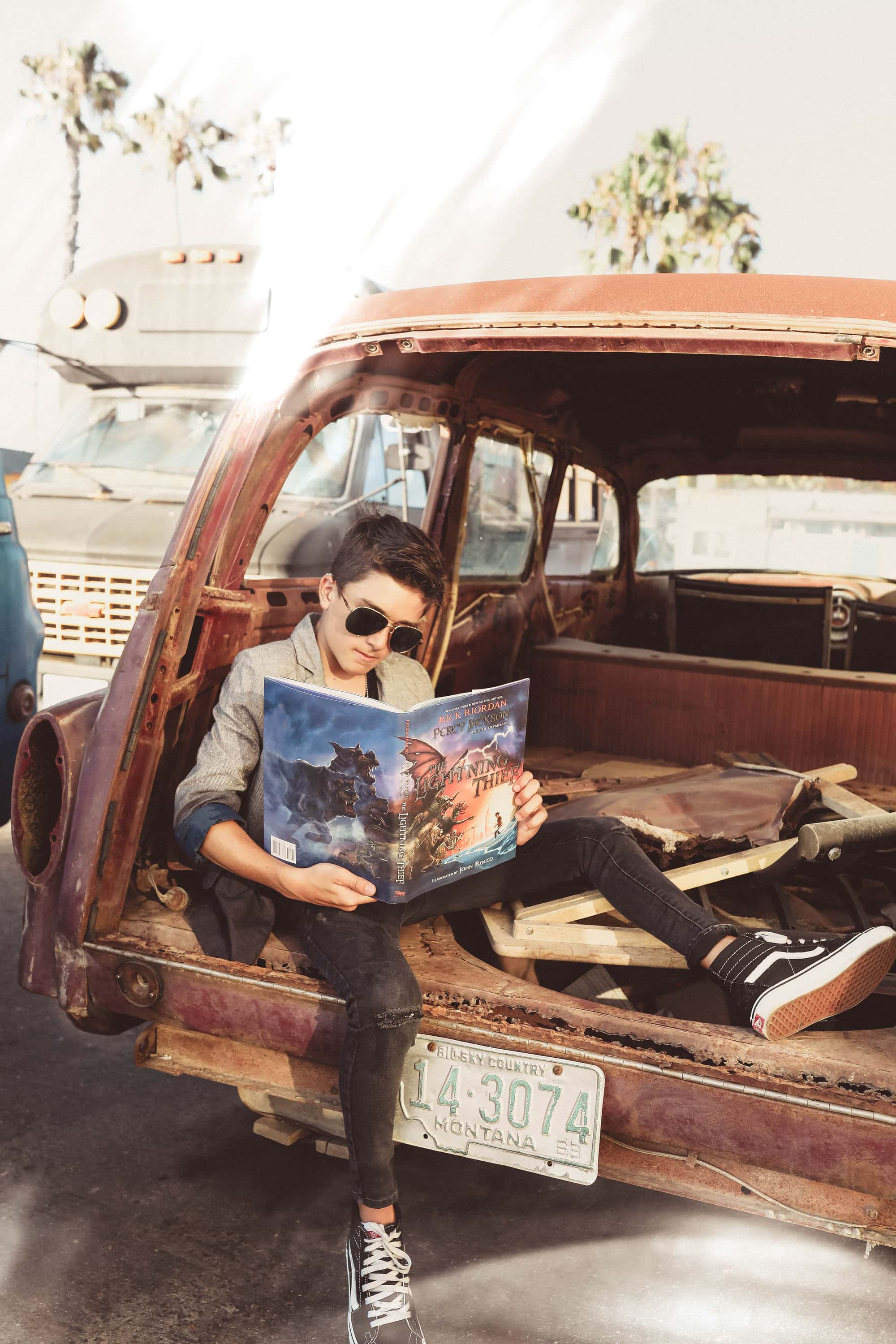 boy reading a book in old car