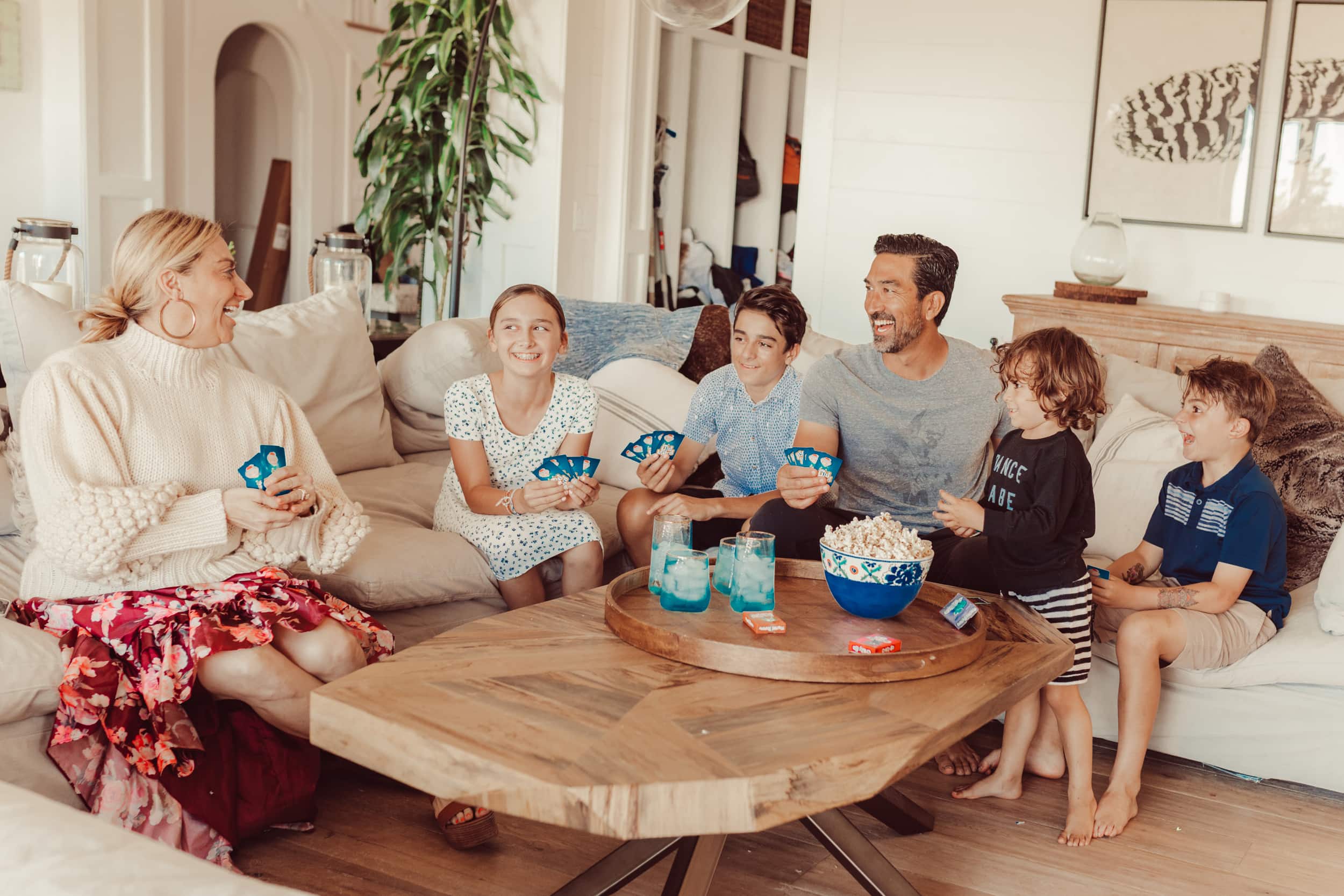 A family of six gathers on a white couch for family game night.