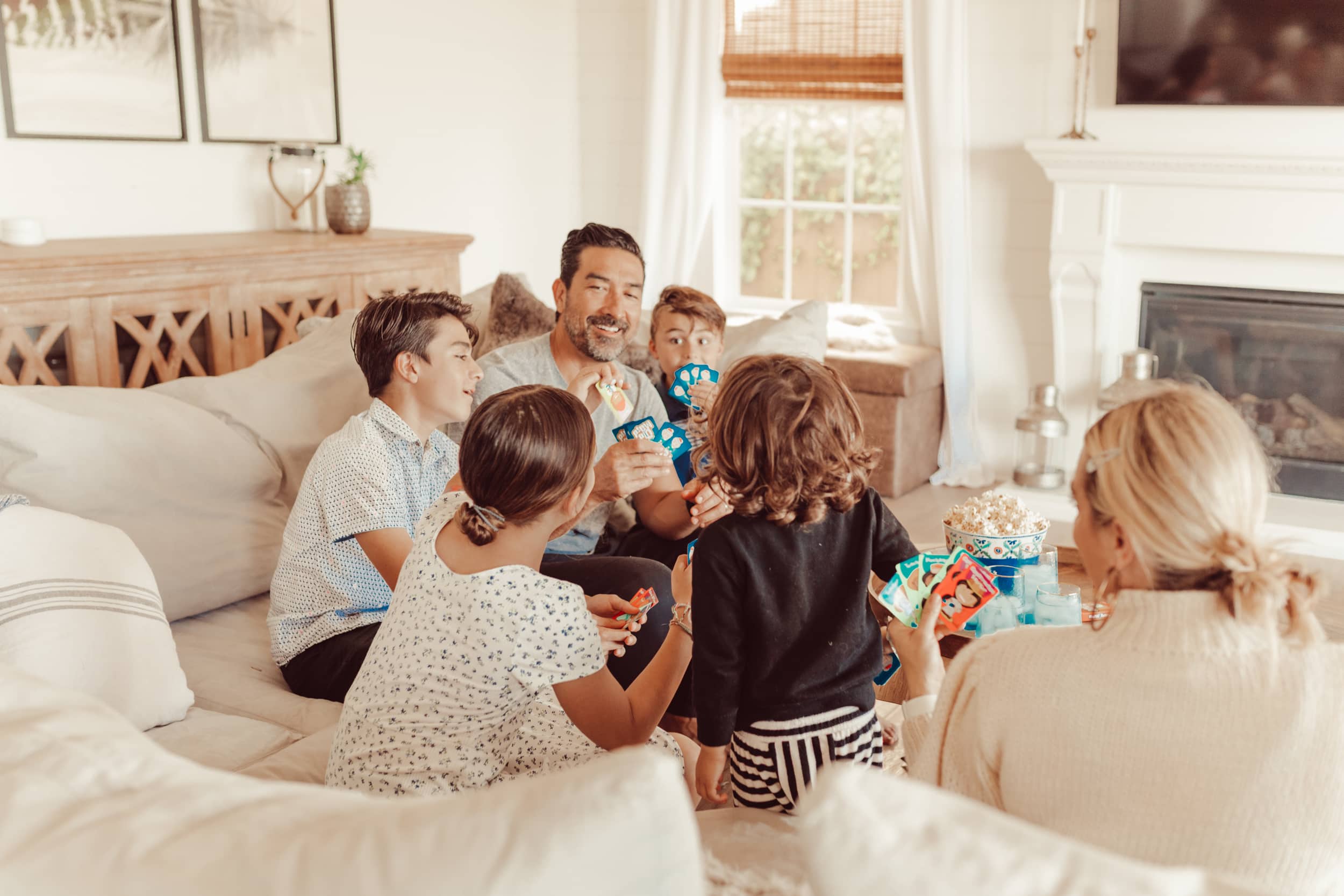 A family of six sitting on the couch playing board games.