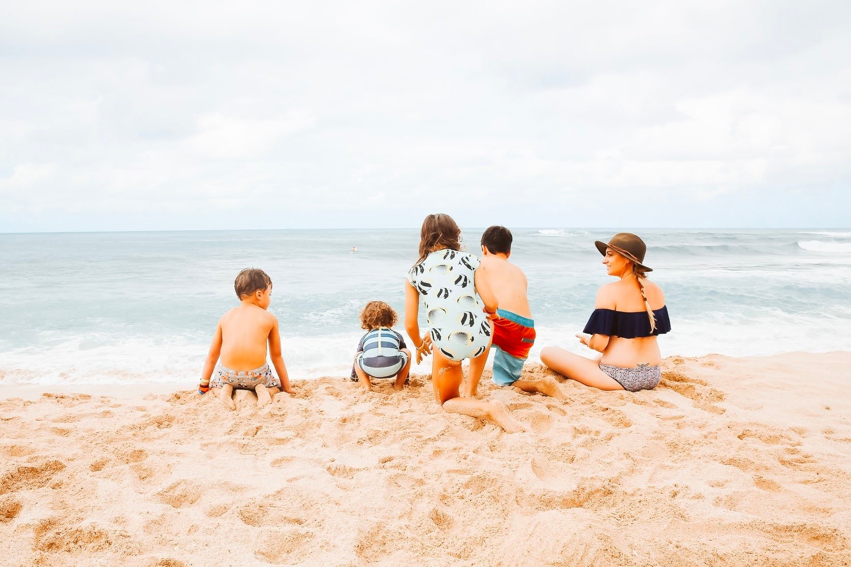 A mom with her four kids playing on the beach.