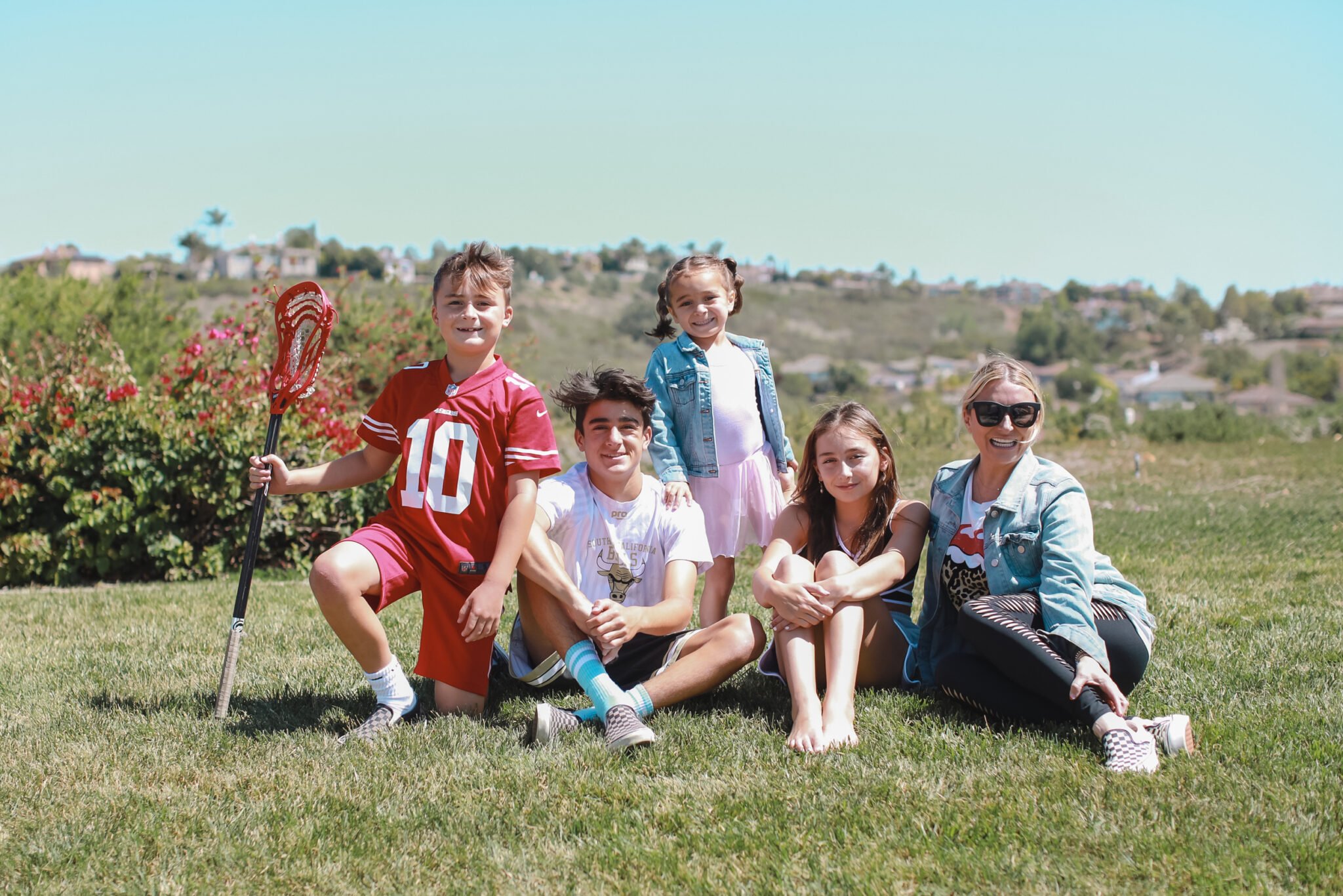 A mom and her four kids sit on the grass.