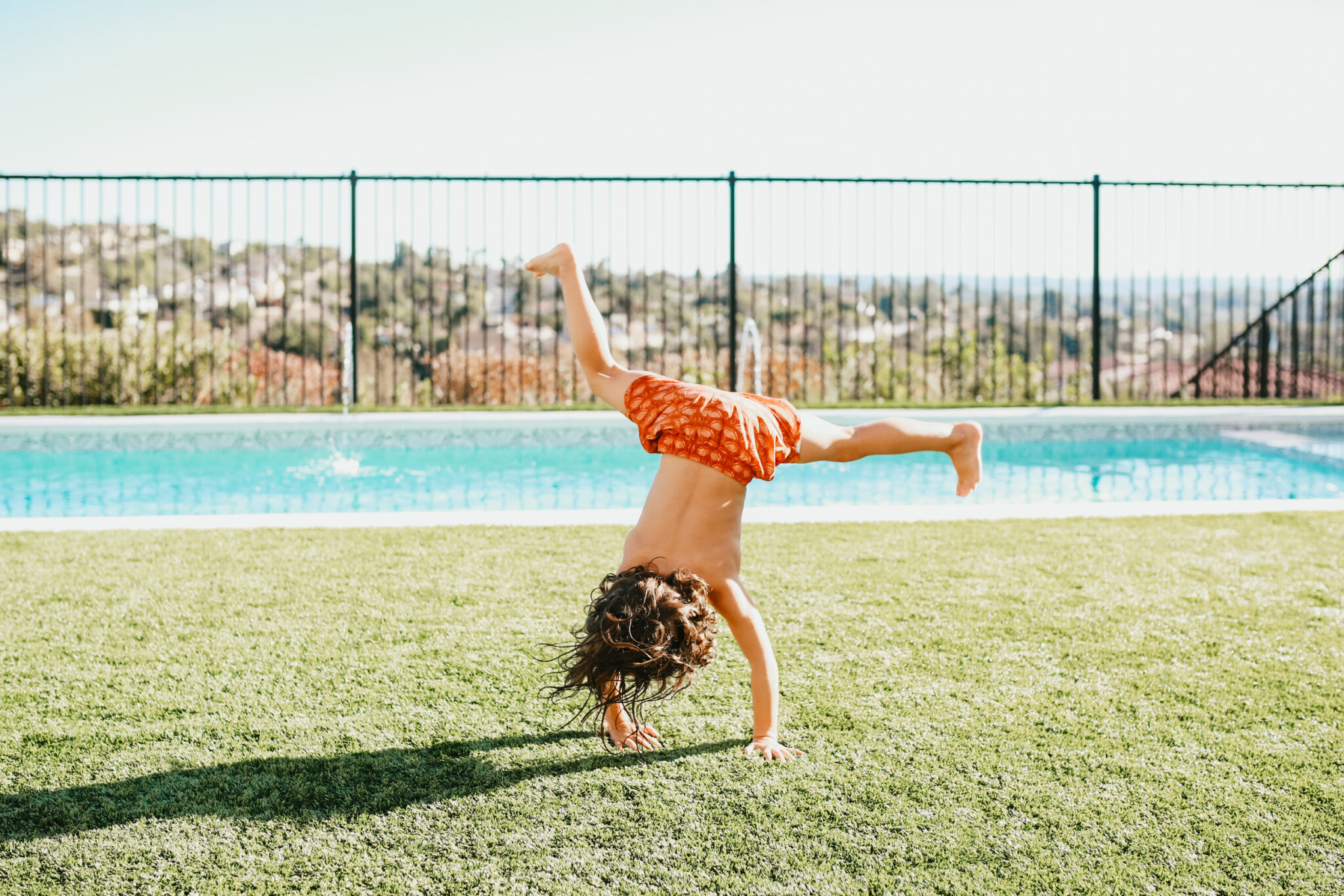 kid doing a cartwheel outdoors by a pool