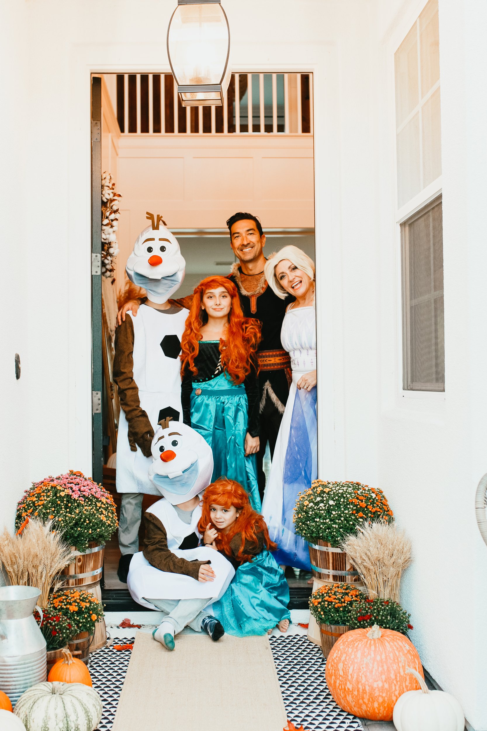 A family stands at their front door during Halloween in matching Frozen costumes.