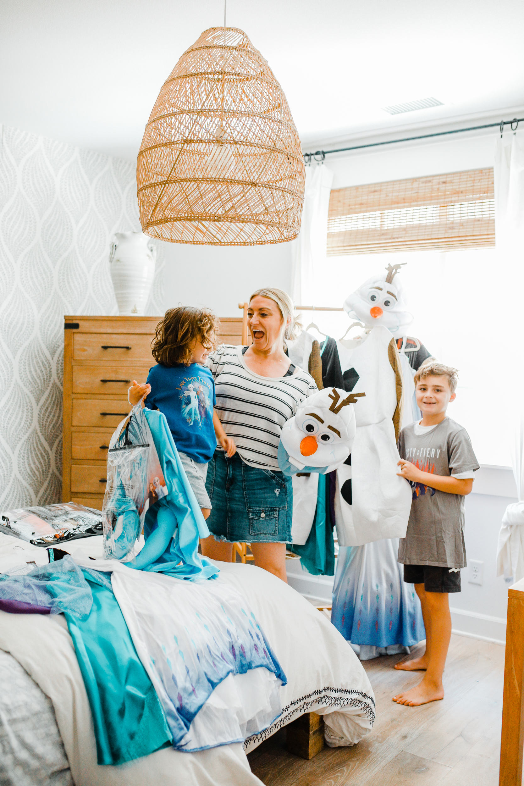 A mom helping her two sons get dressed in Halloween costumes. 