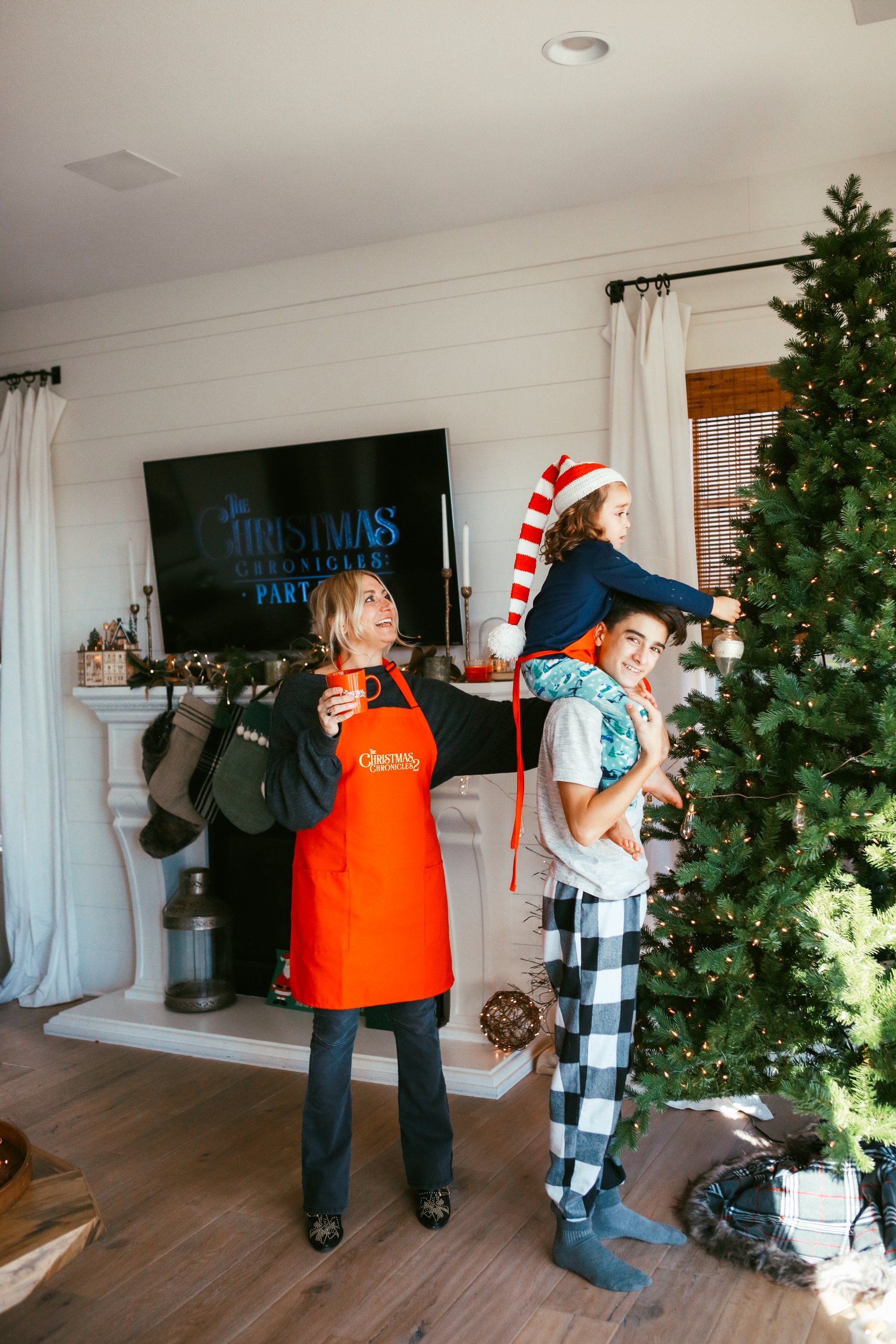 mom helping her kids decorate the christmas tree