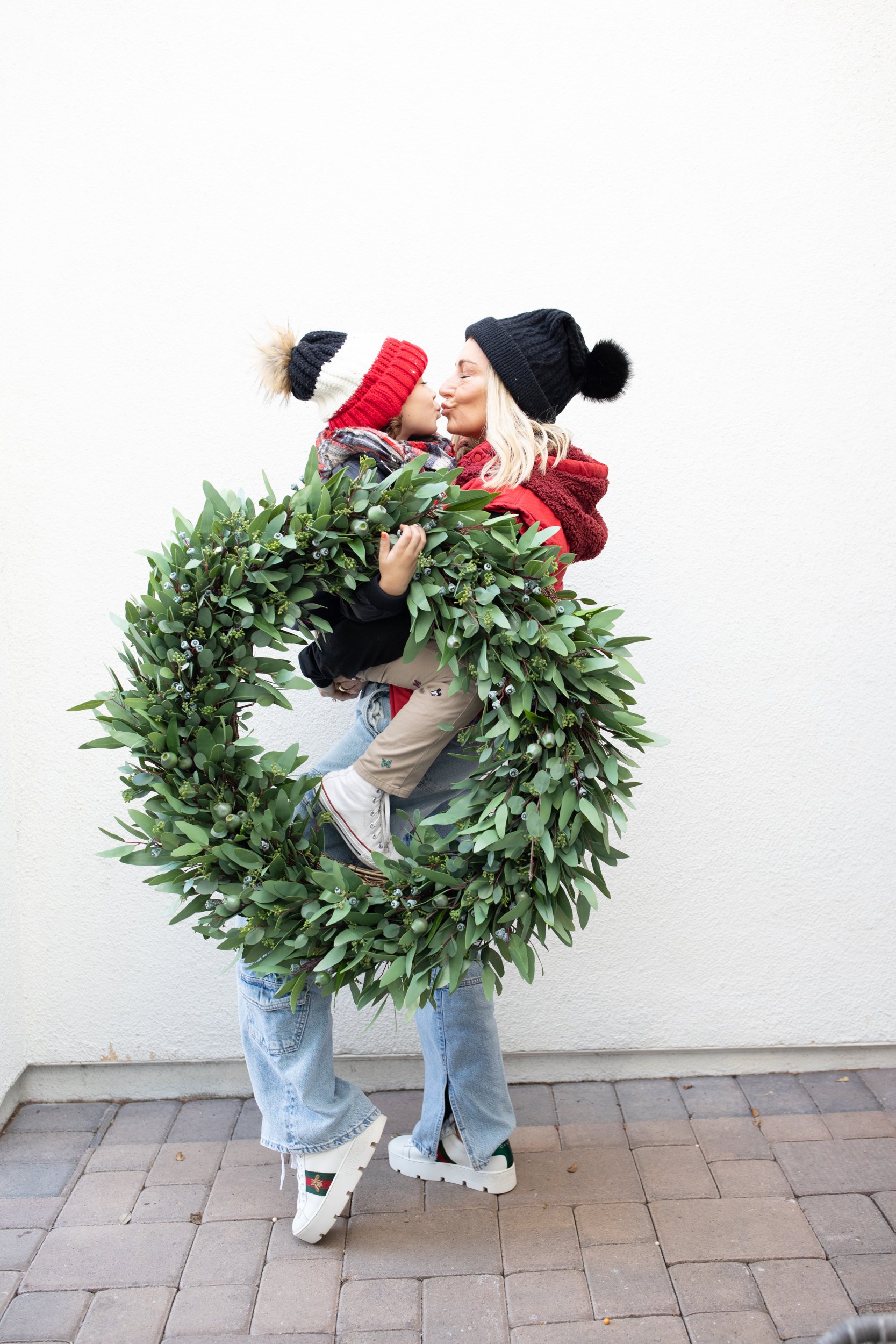 mom holding her toddler and a wreath