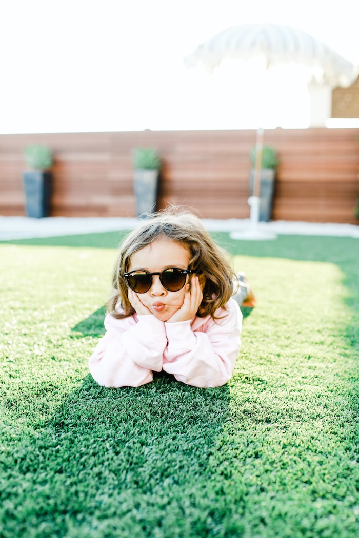 child in sunglasses laying on grass