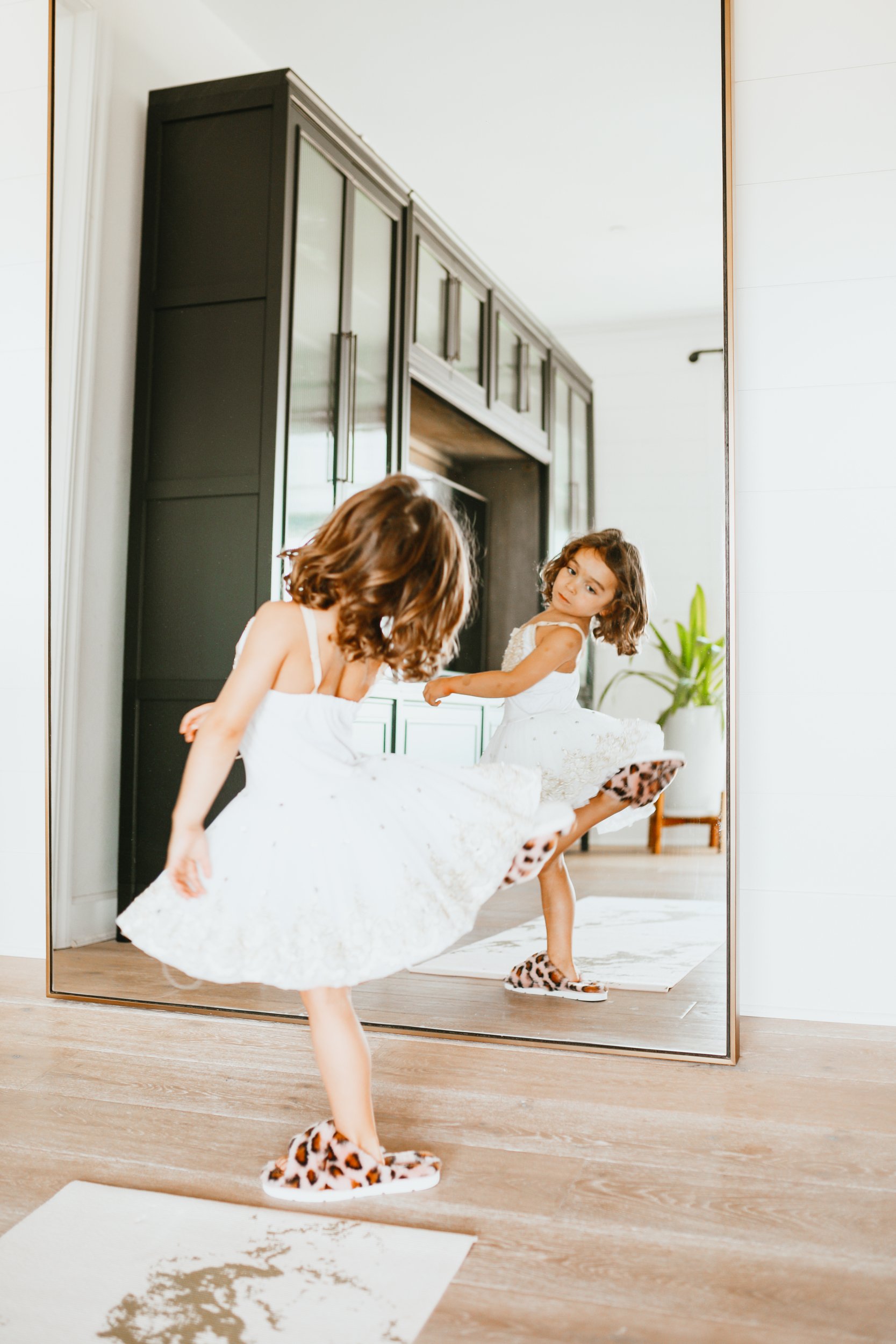 toddler in a dress dancing in front of the mirror