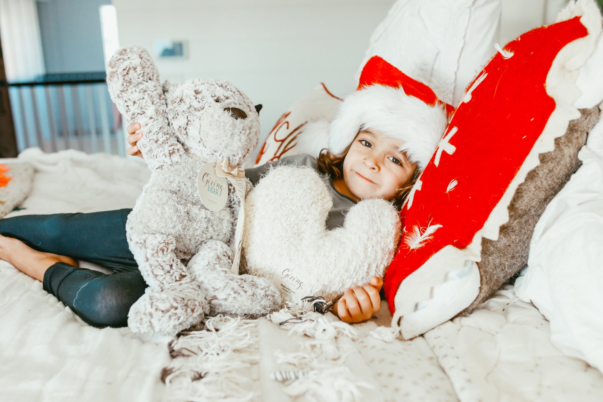 boy on bed with teddy bear and santa hat