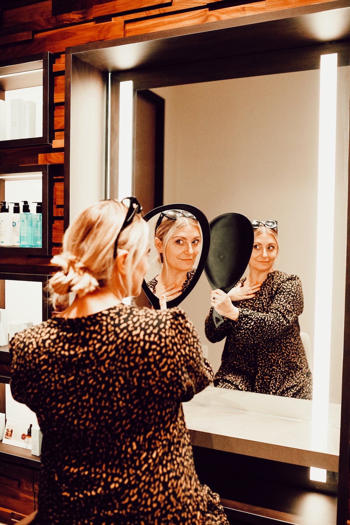 A blonde woman looks at herself in a hand-held mirror before getting a medical procedure.