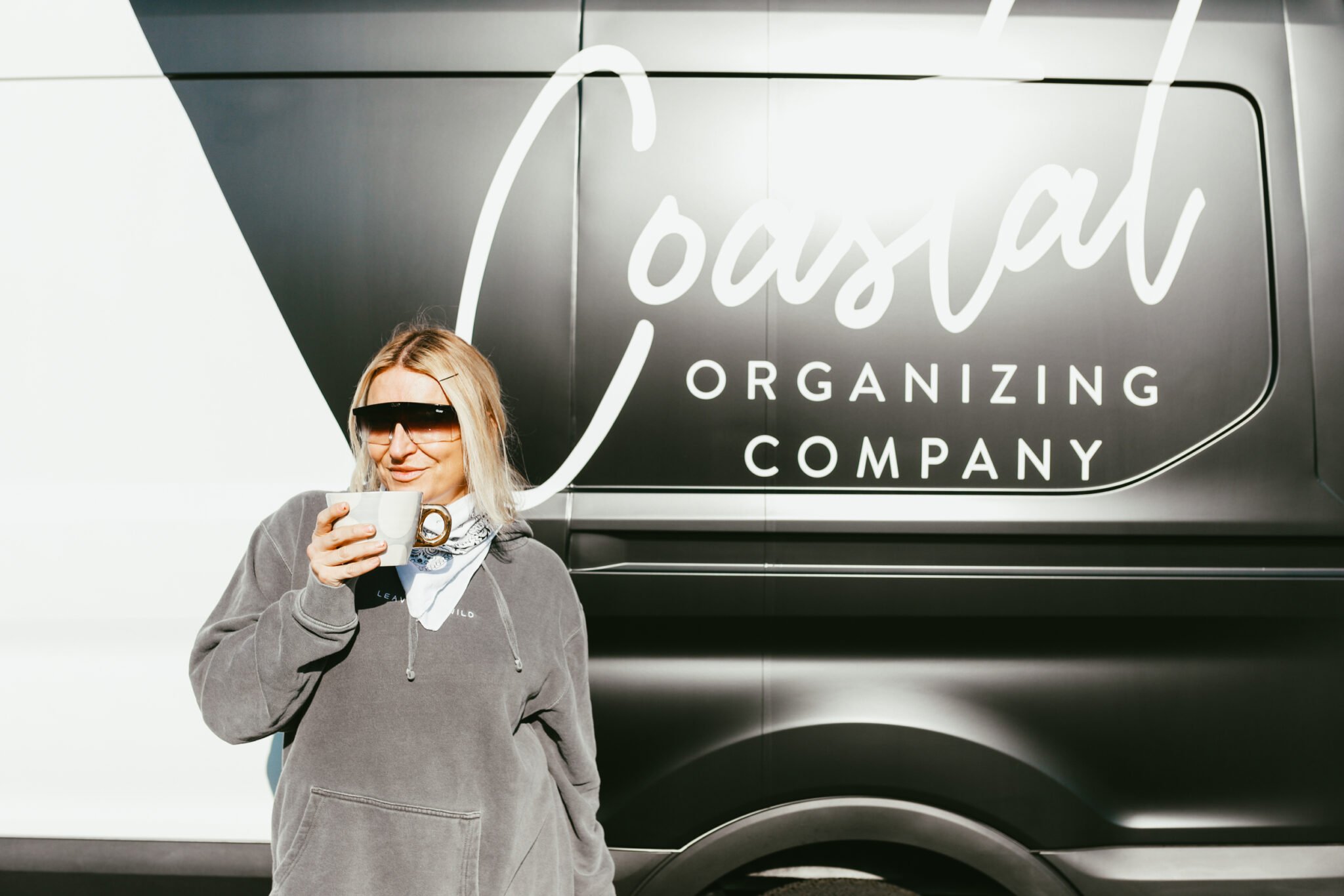 woman drinking coffee by coastal organizing company van