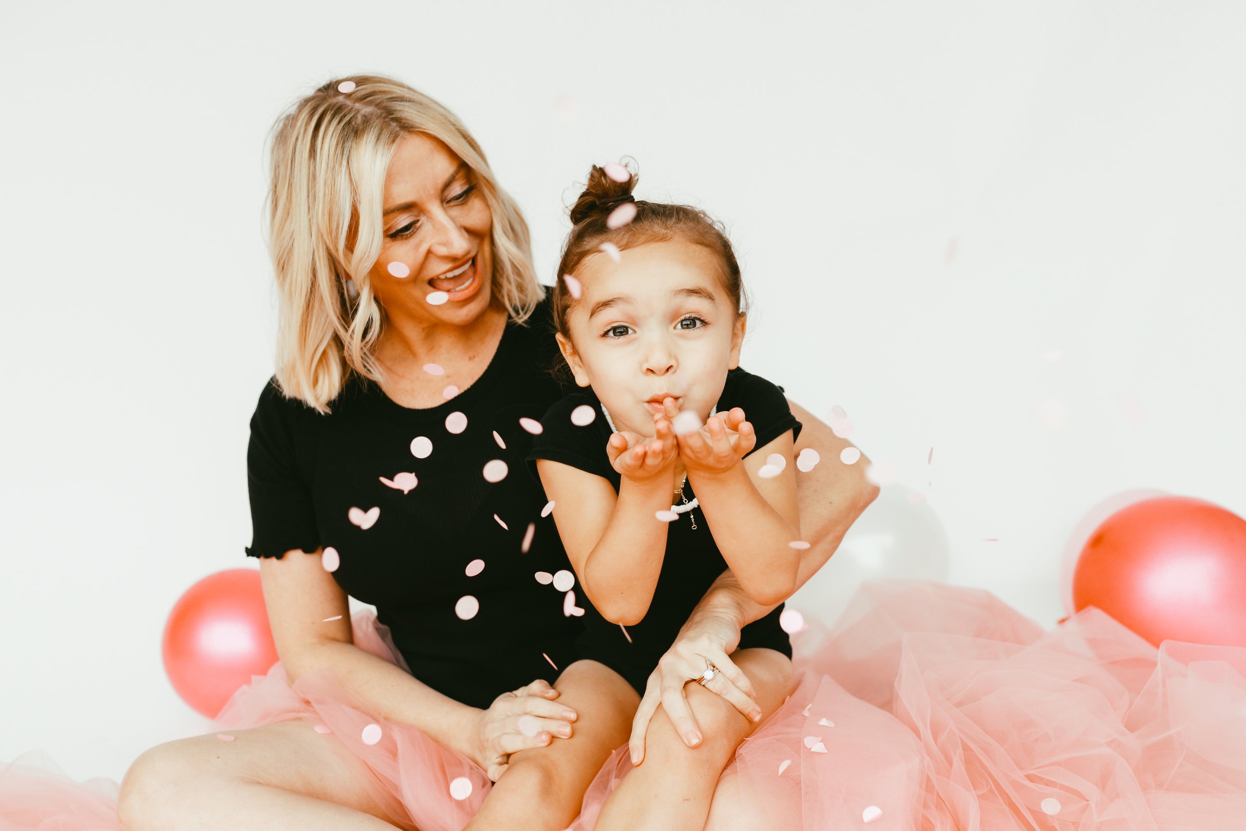 mom holding child blowing confetti