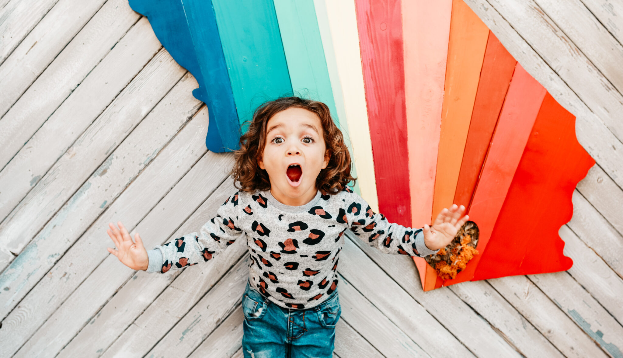 happy toddler by rainbow wall