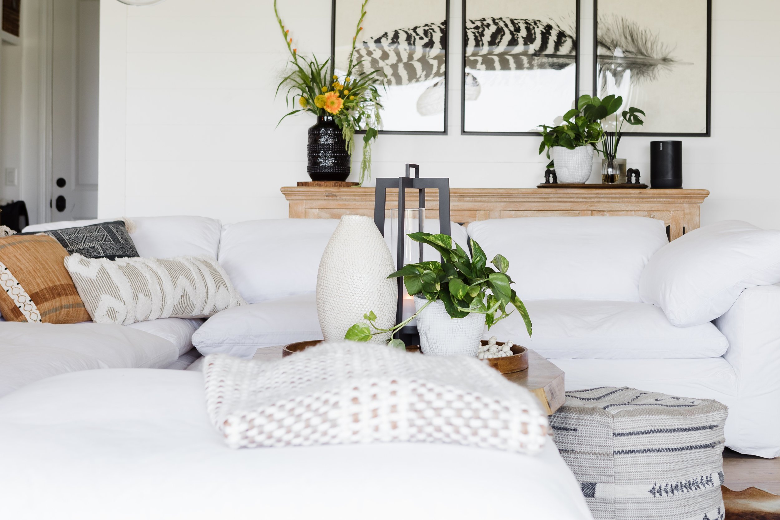 Blankets and throw pillows on a white couch in a living room.