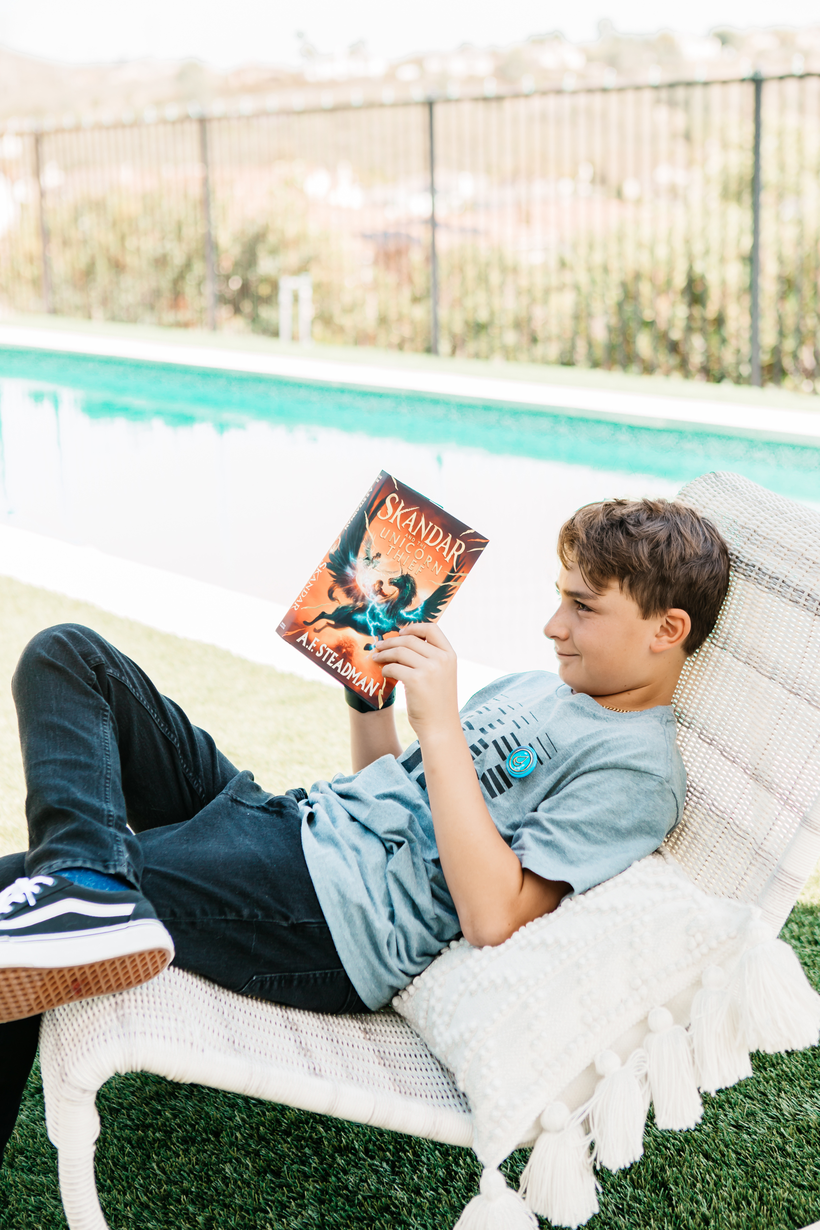 boy reading a book by a pool