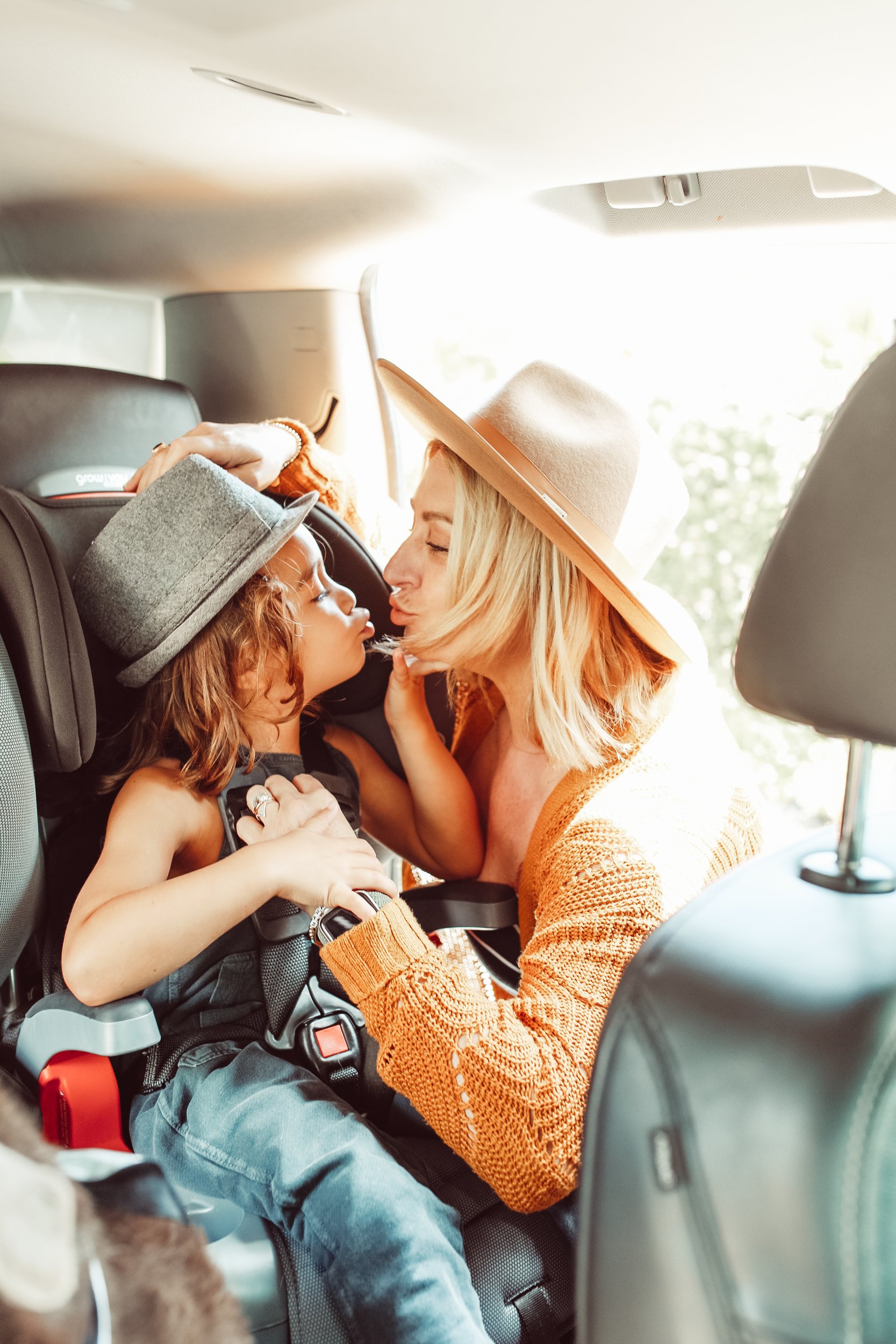 mom kissing toddler in car seat