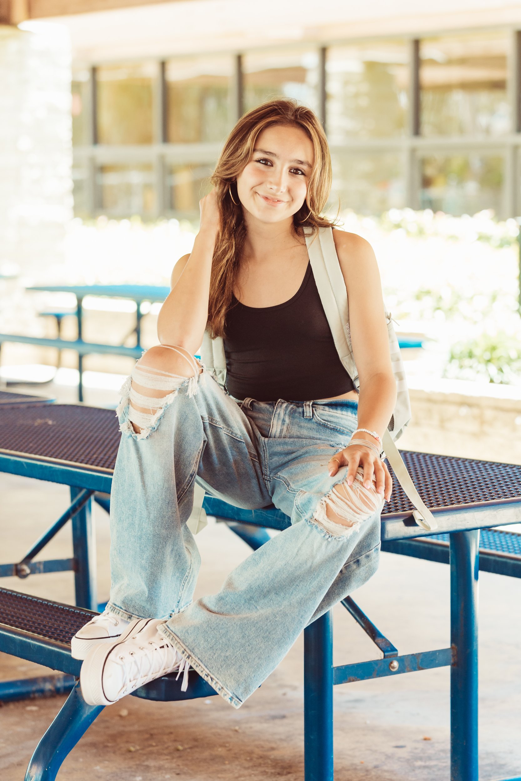 girl sitting on school bench with backpack