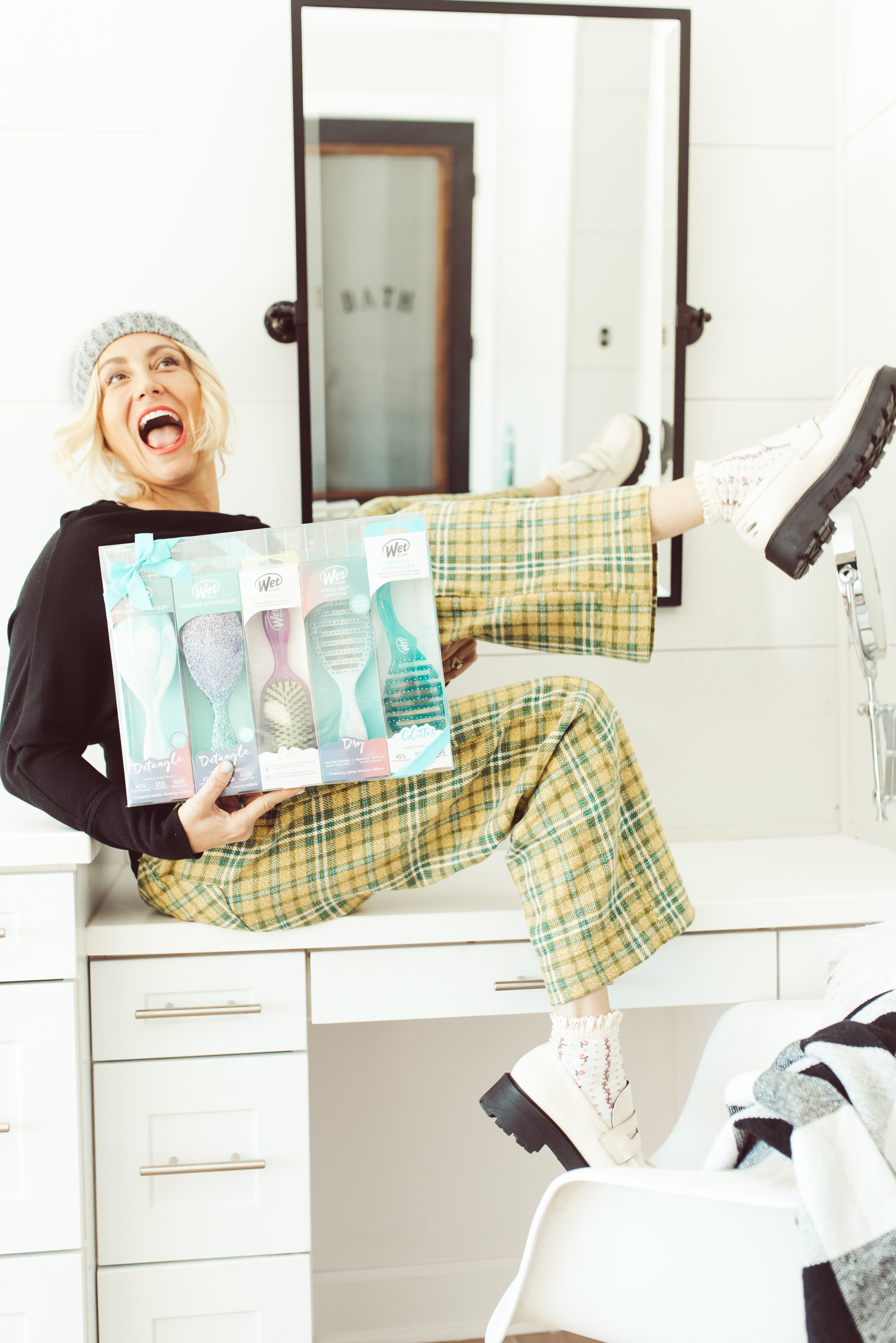 woman holding brush set laughing in bathroom