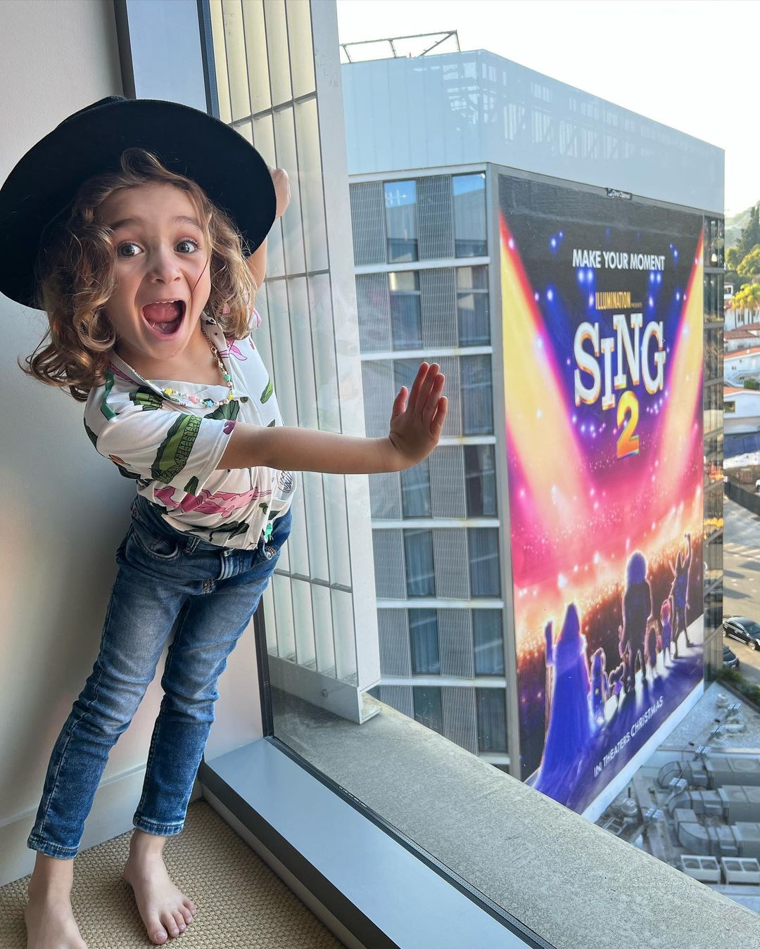 boy standing by window in with movie premiere sign