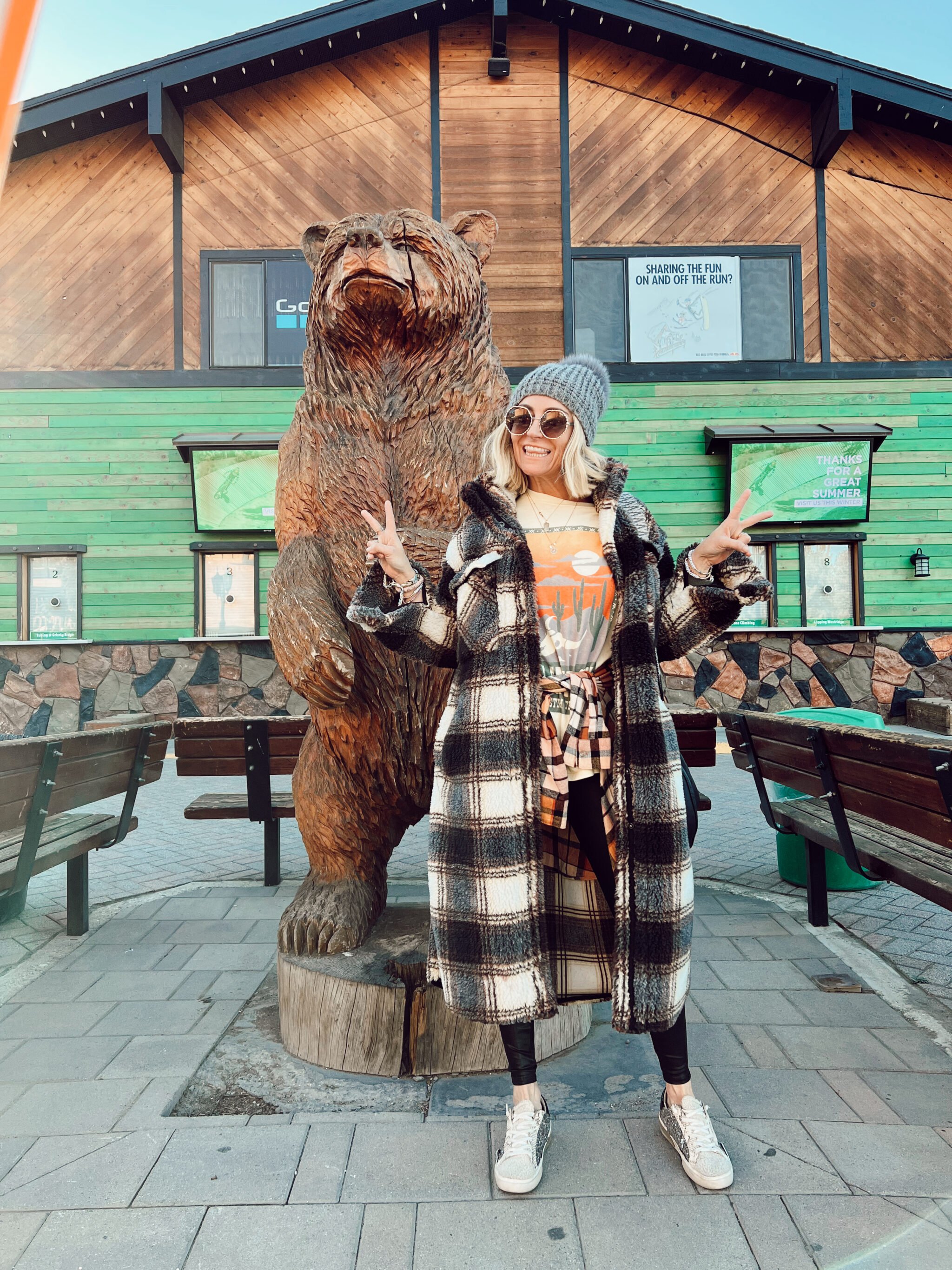 woman in front of big wooden bear