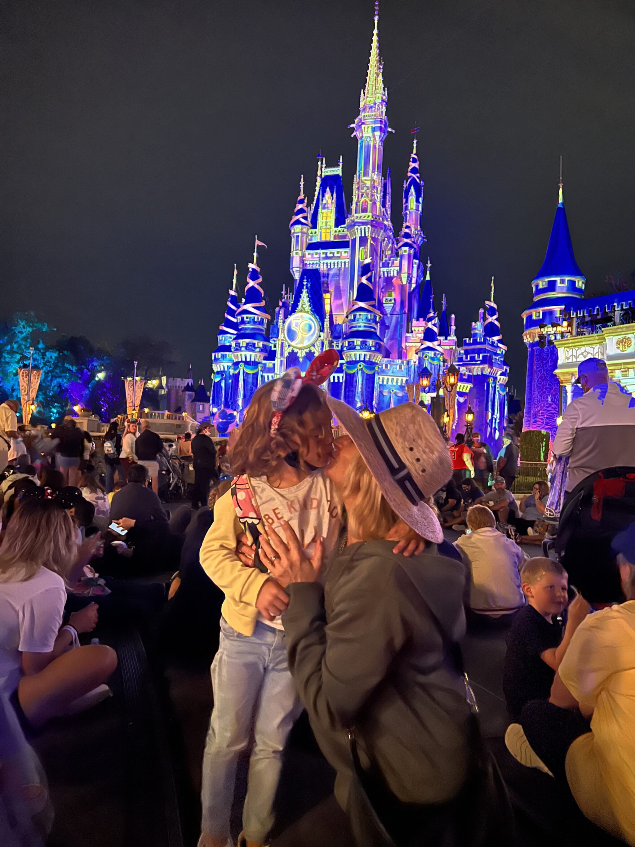 mom kissing child by disney castle