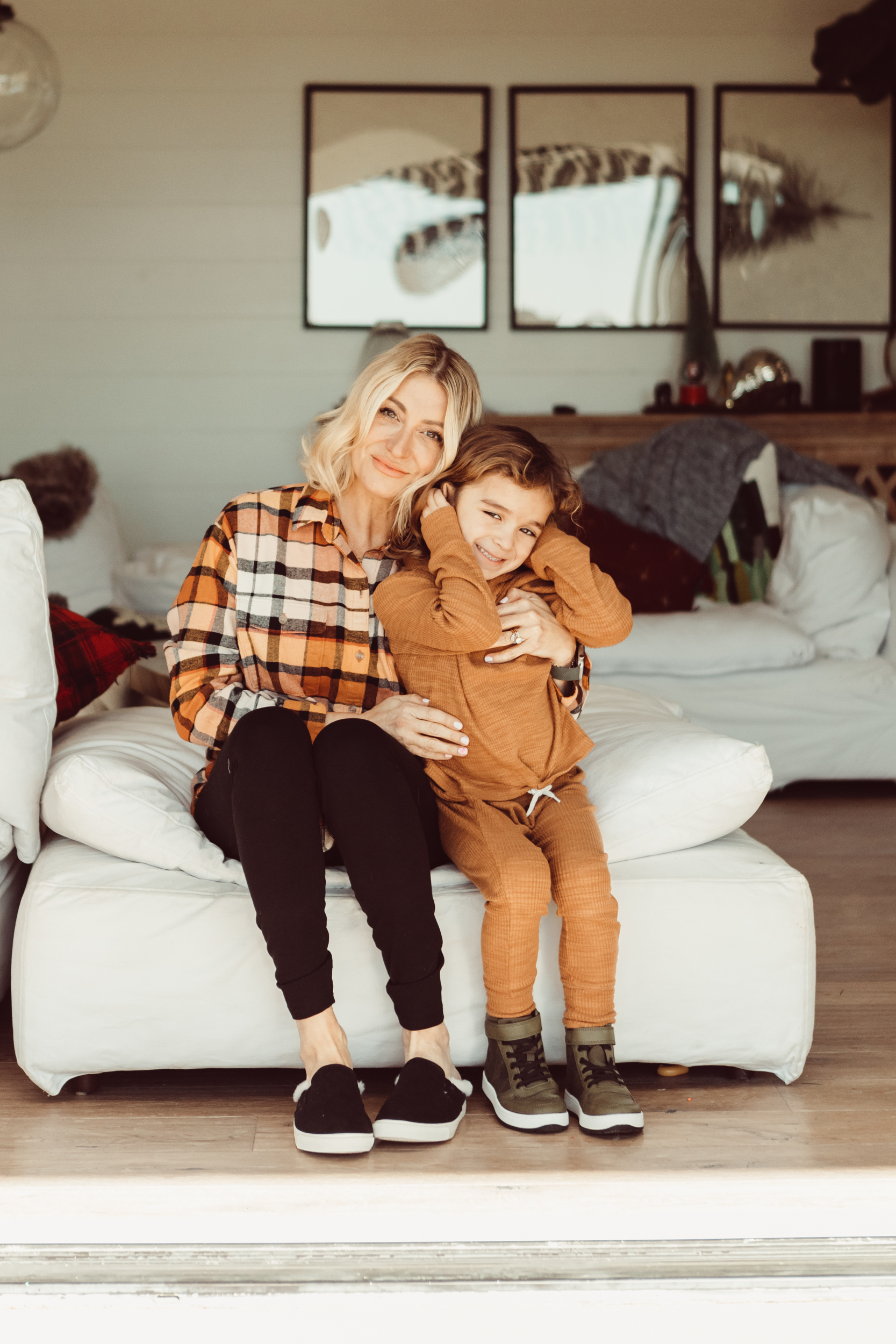 A mom and son sitting on the couch hugging.