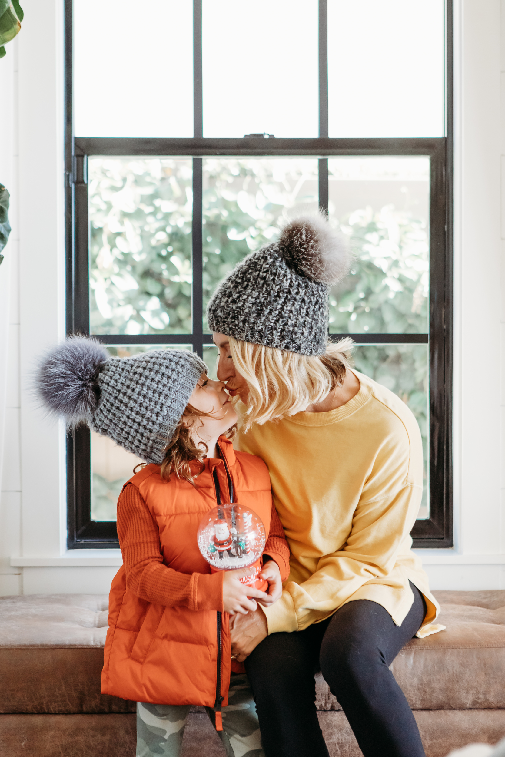 mom and child kissing holding christmas snow globe