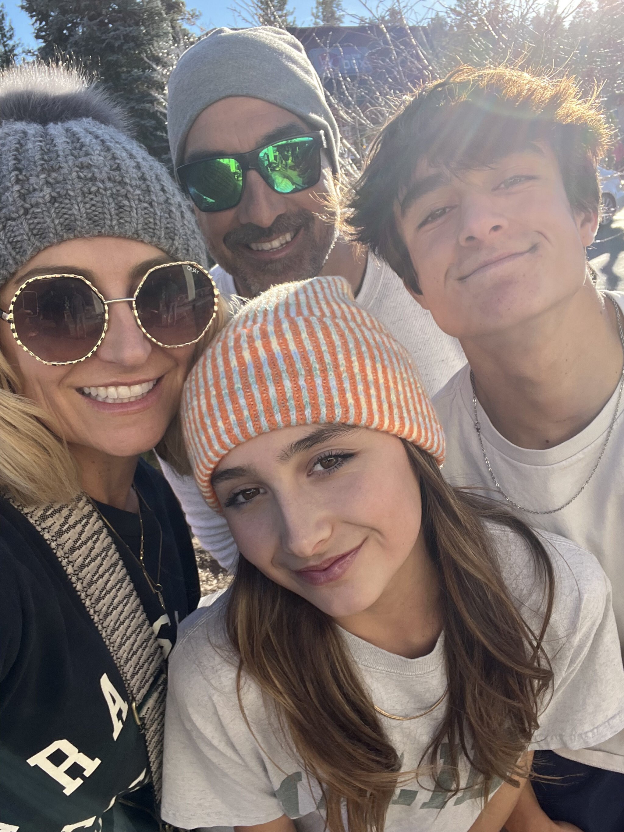A mom and dad take a selfie with their two teenagers.