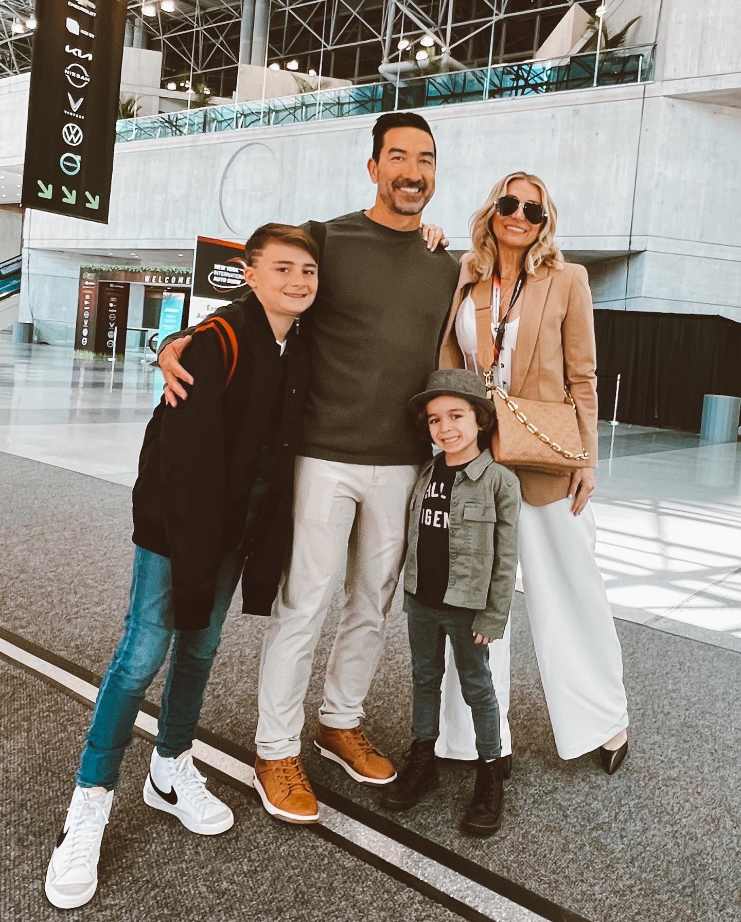 A mom and dad and their two sons pose for a picture at an airport.