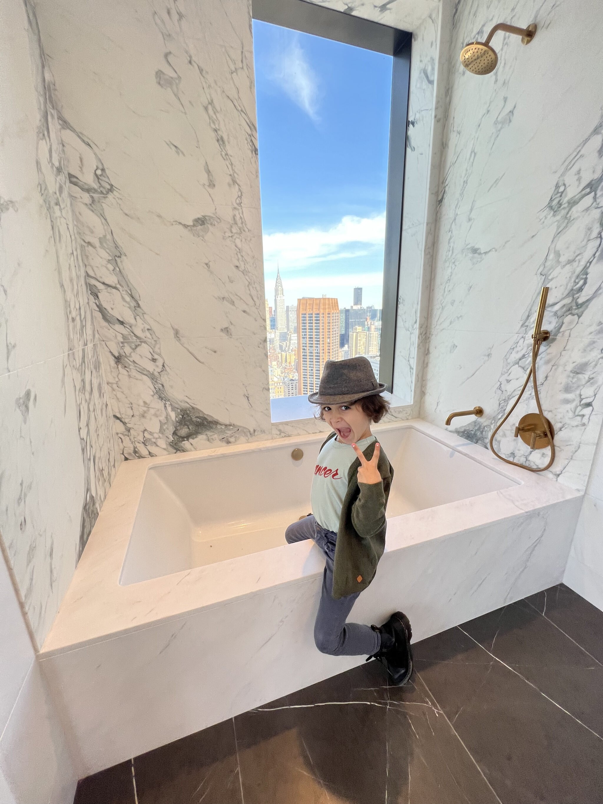 kid sitting on the side of a marble tub