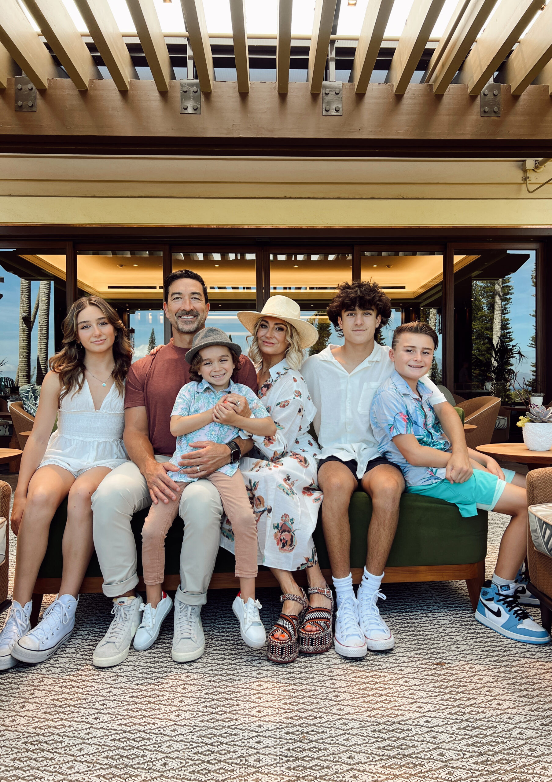 A family of six is sitting together on a small bench.