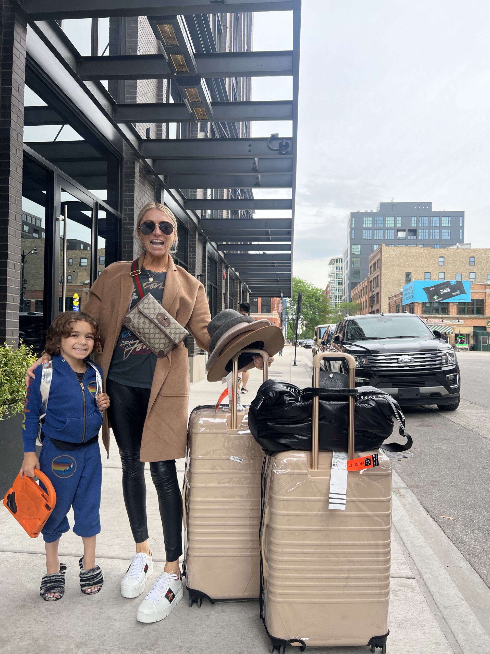 mom and son on sidewalk with luggage