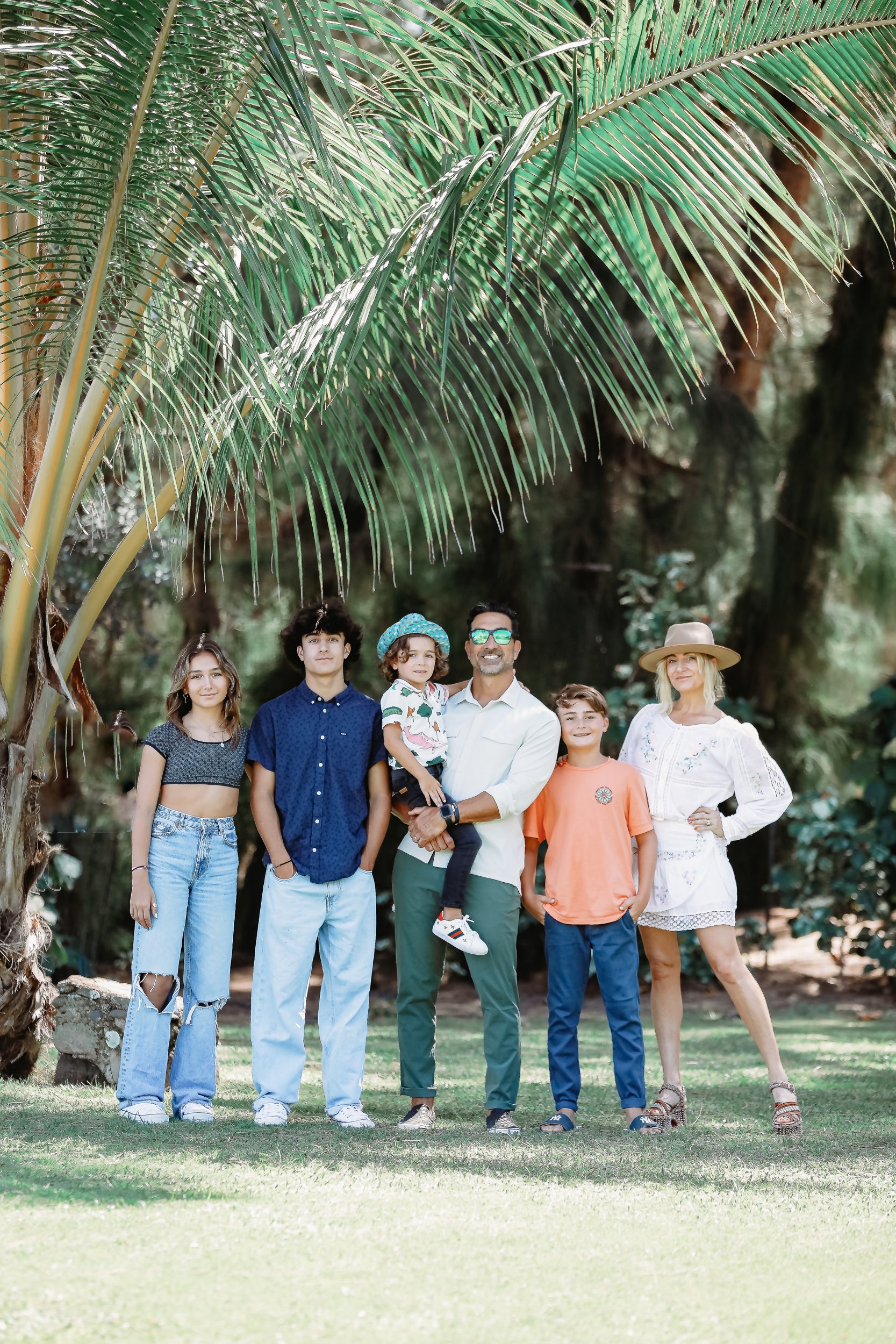 family standing together under a palm tree