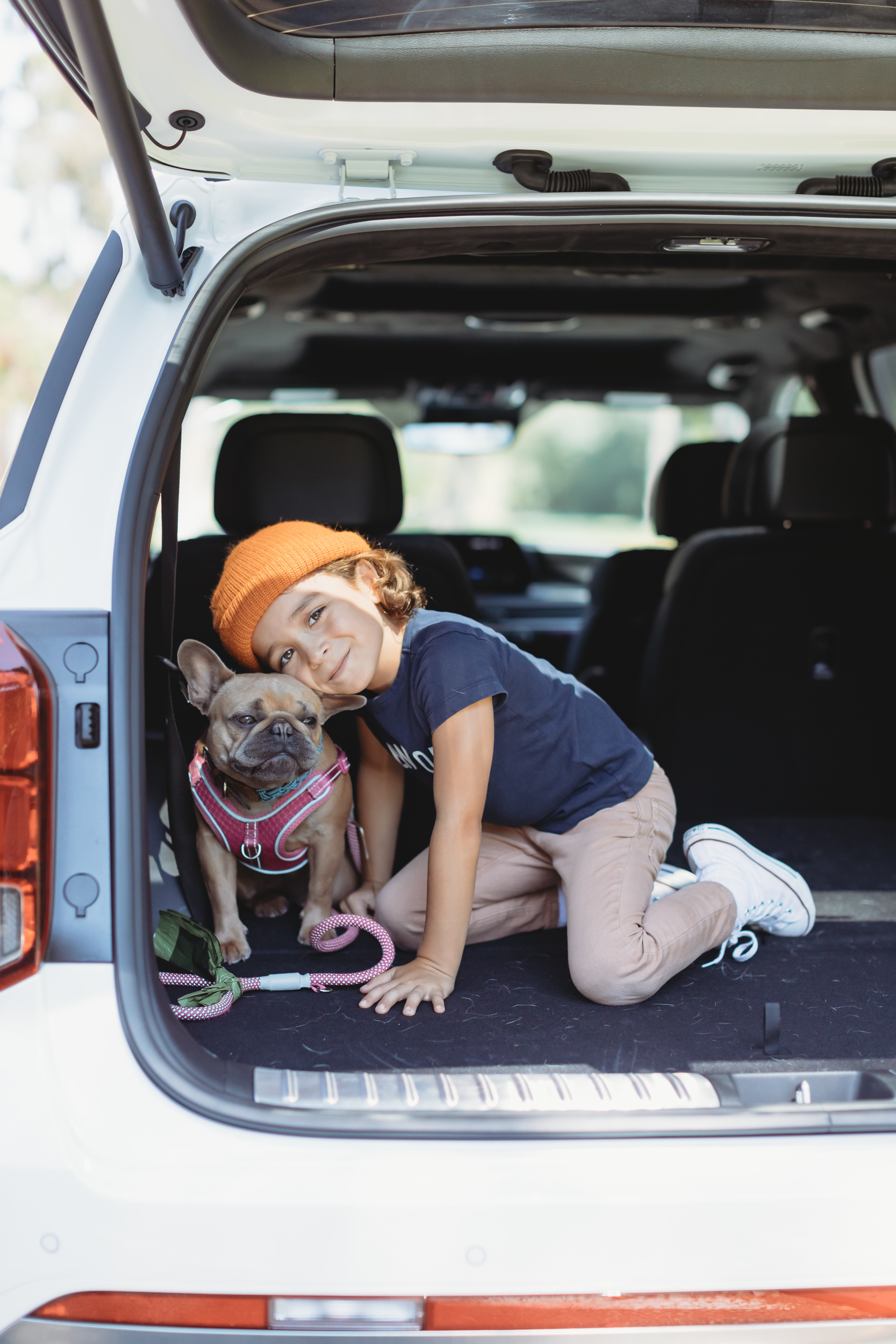boy hugging his dog in back of SUV