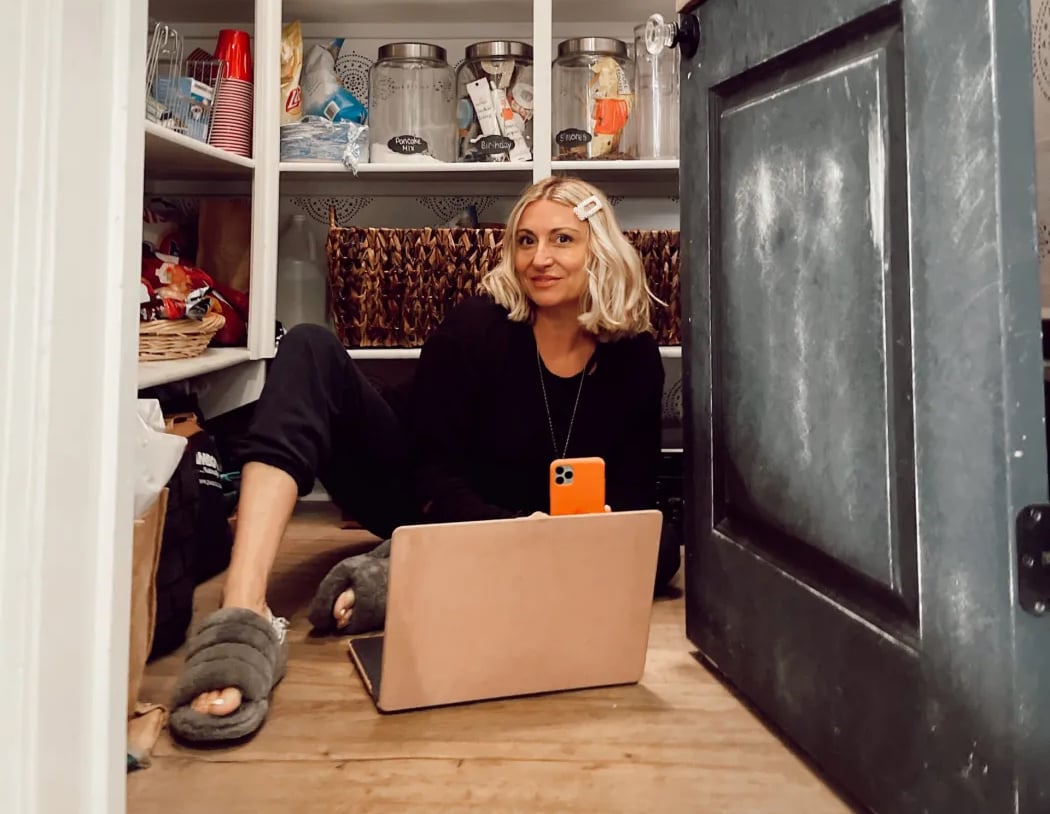 woman sitting in a closet with laptop