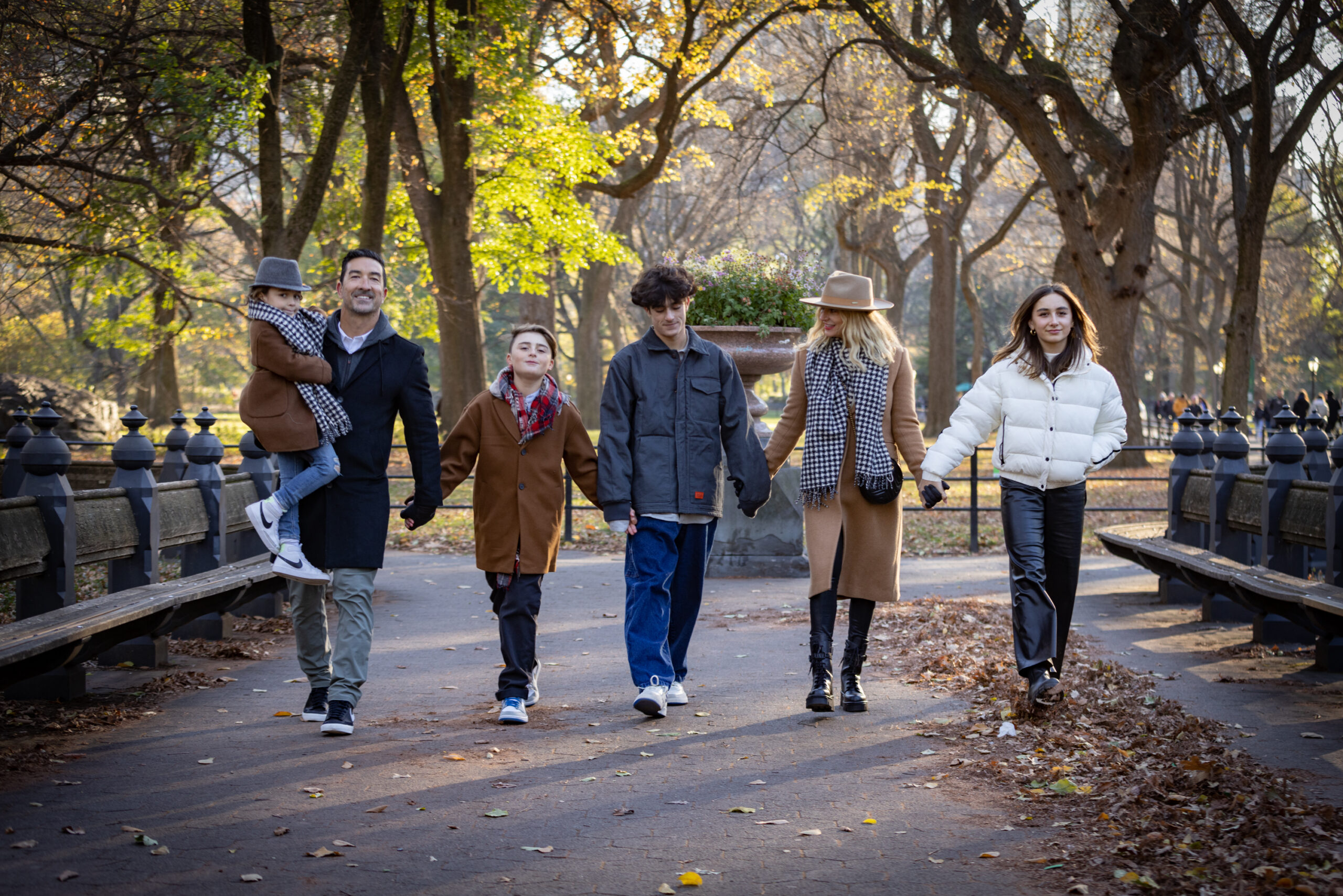A family of six walks through Central Park holding hands.
