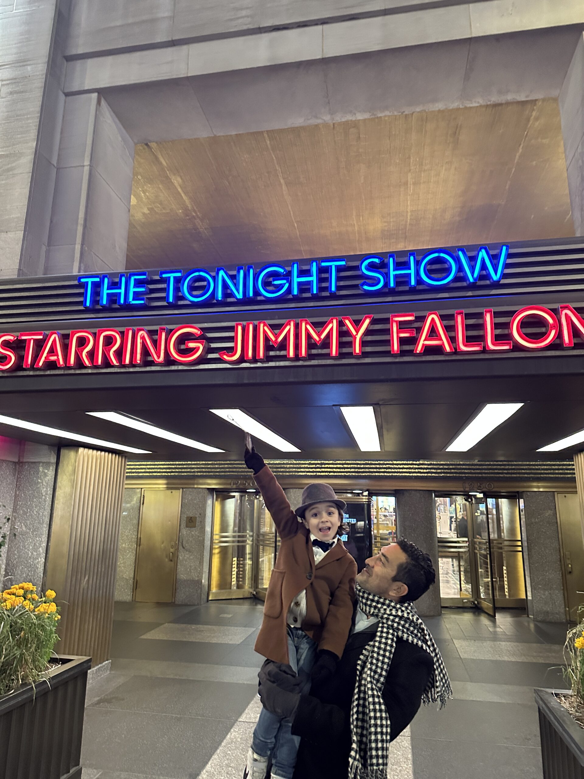 dad holding up son by tonight show sign