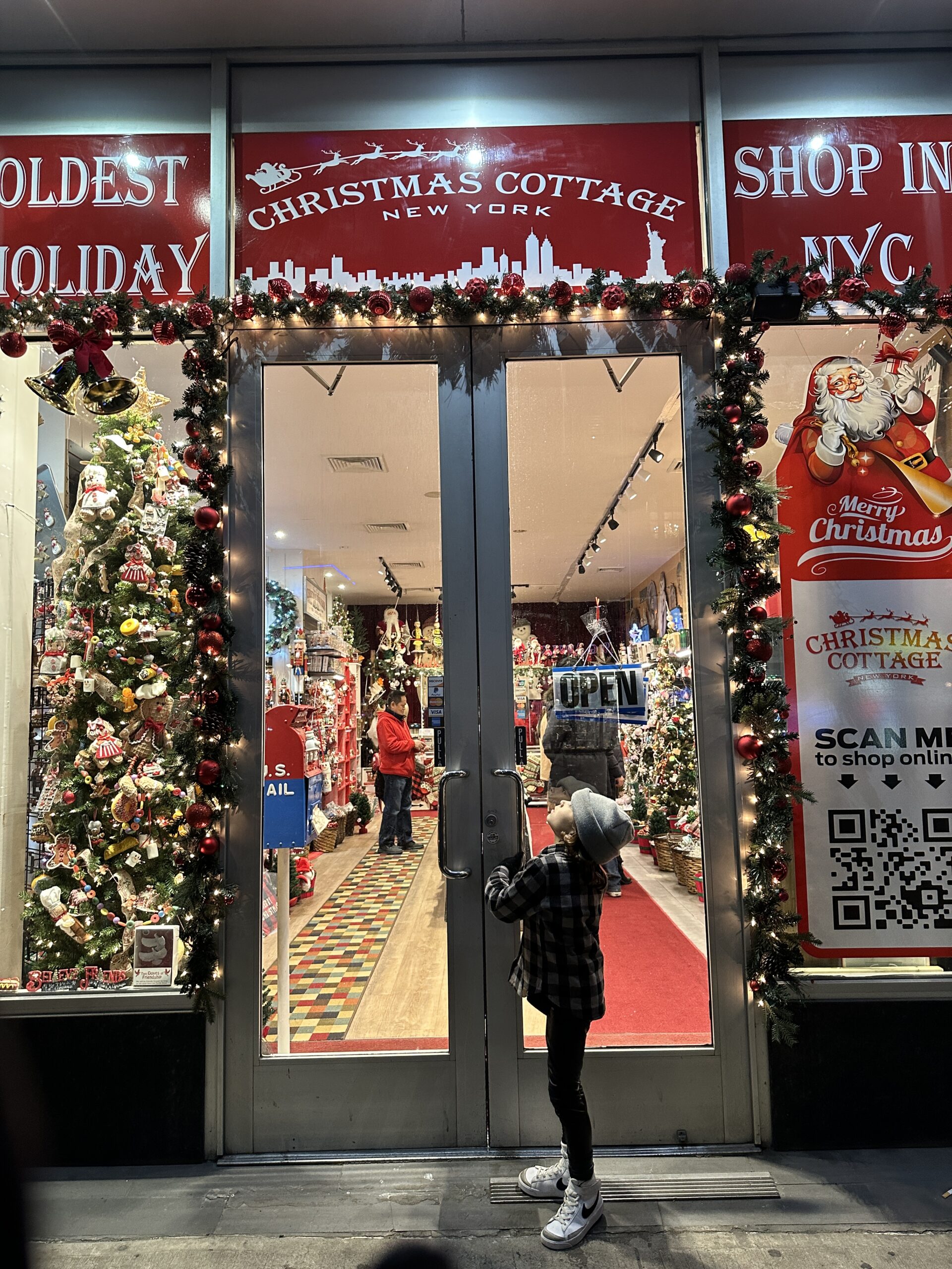 child in front of christmas shop