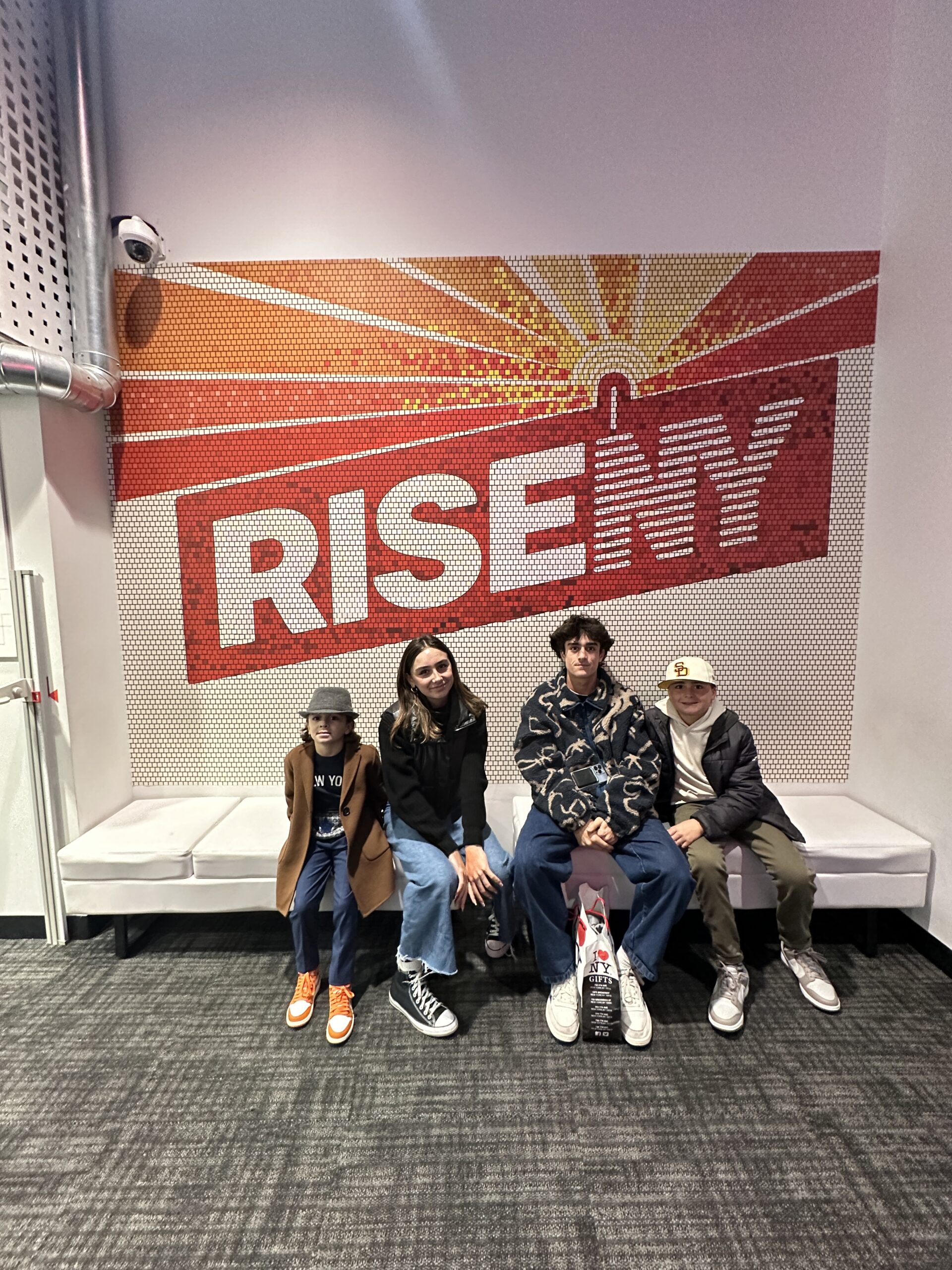 kids sitting by rise ny sign